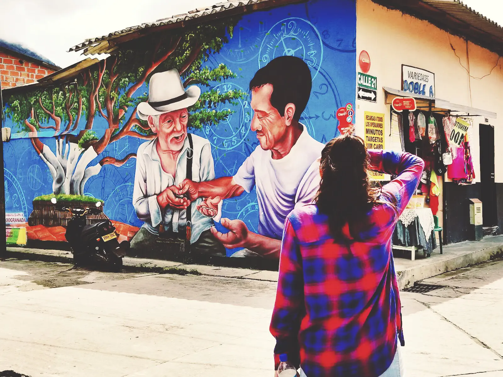 woman standing in front of a mural of Colombian farmers on a wall