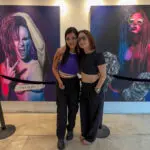two brunette girls standing in front of grafitti art