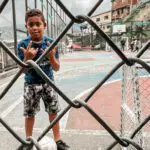 Colombian kid on a concrete soccer field, throwing up gang signs