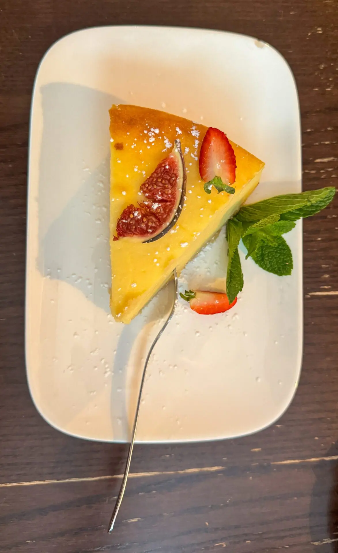 Fruit covered dessert slice on a white plate