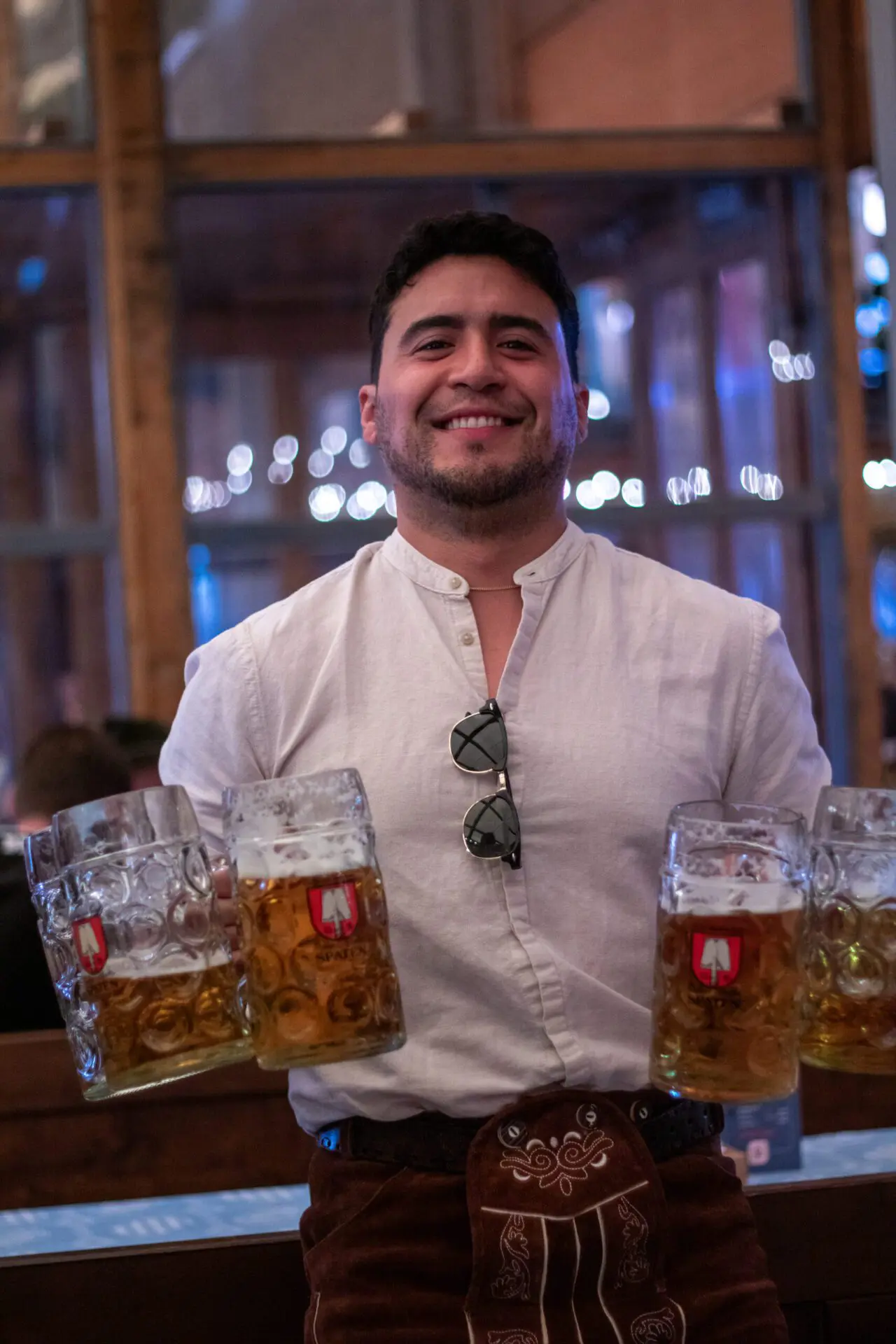 Brunette man in a tracht holding 6 beers