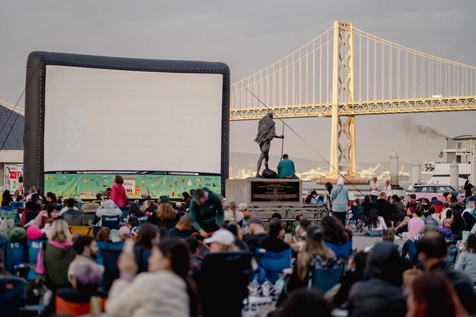 Inflatable movie screen set up with the Bay Bridge lit behind it