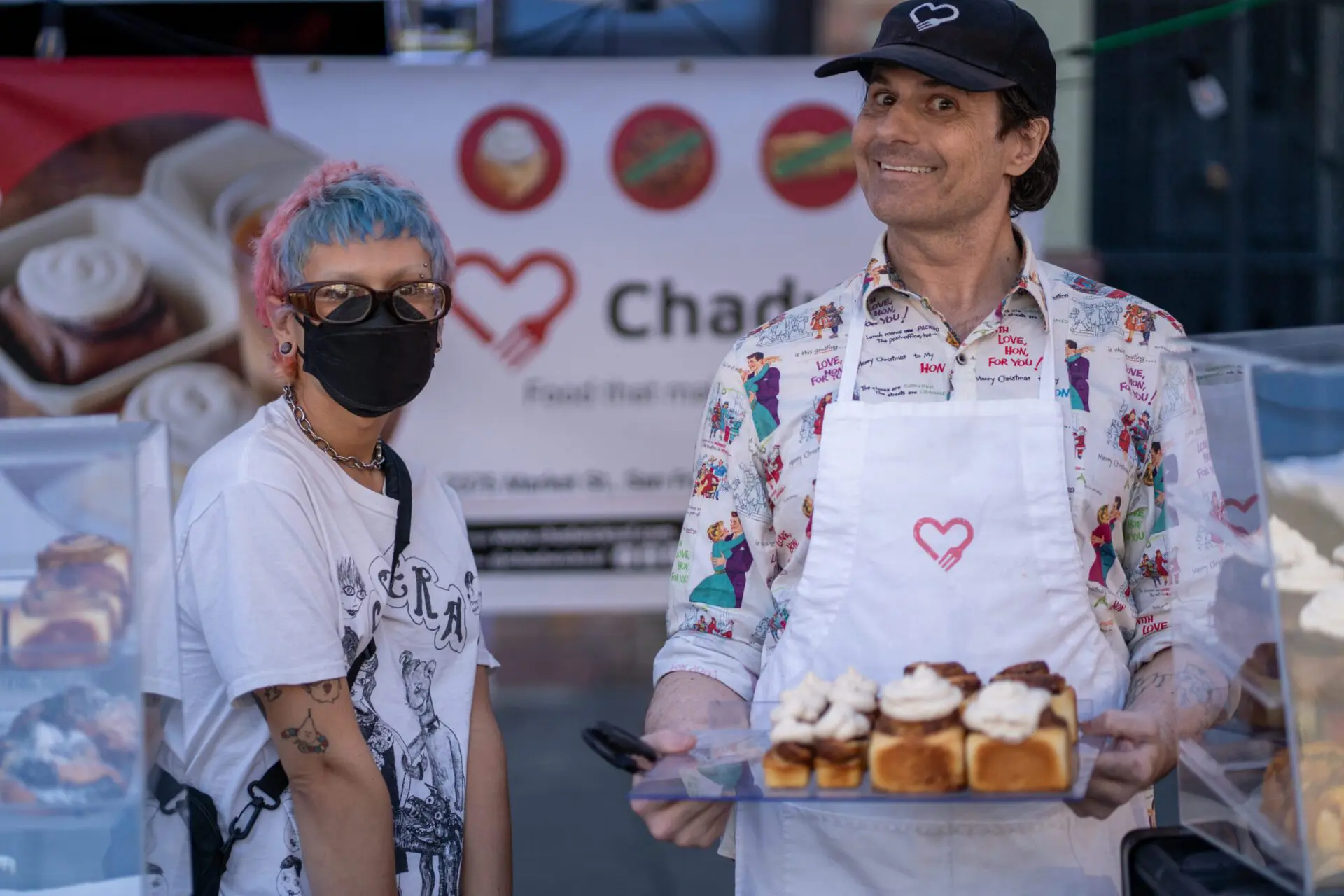 Vendors holding a tray of pastries at their Castro Night Market booth