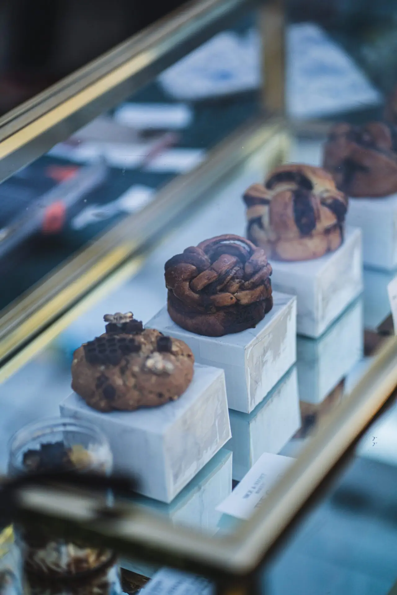 Close-up of pastries displayed on white stands inside a glass case