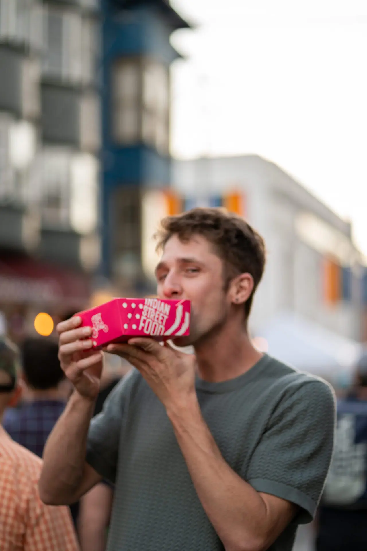 Man laughing and taking a sip from a bright pink drink pouch