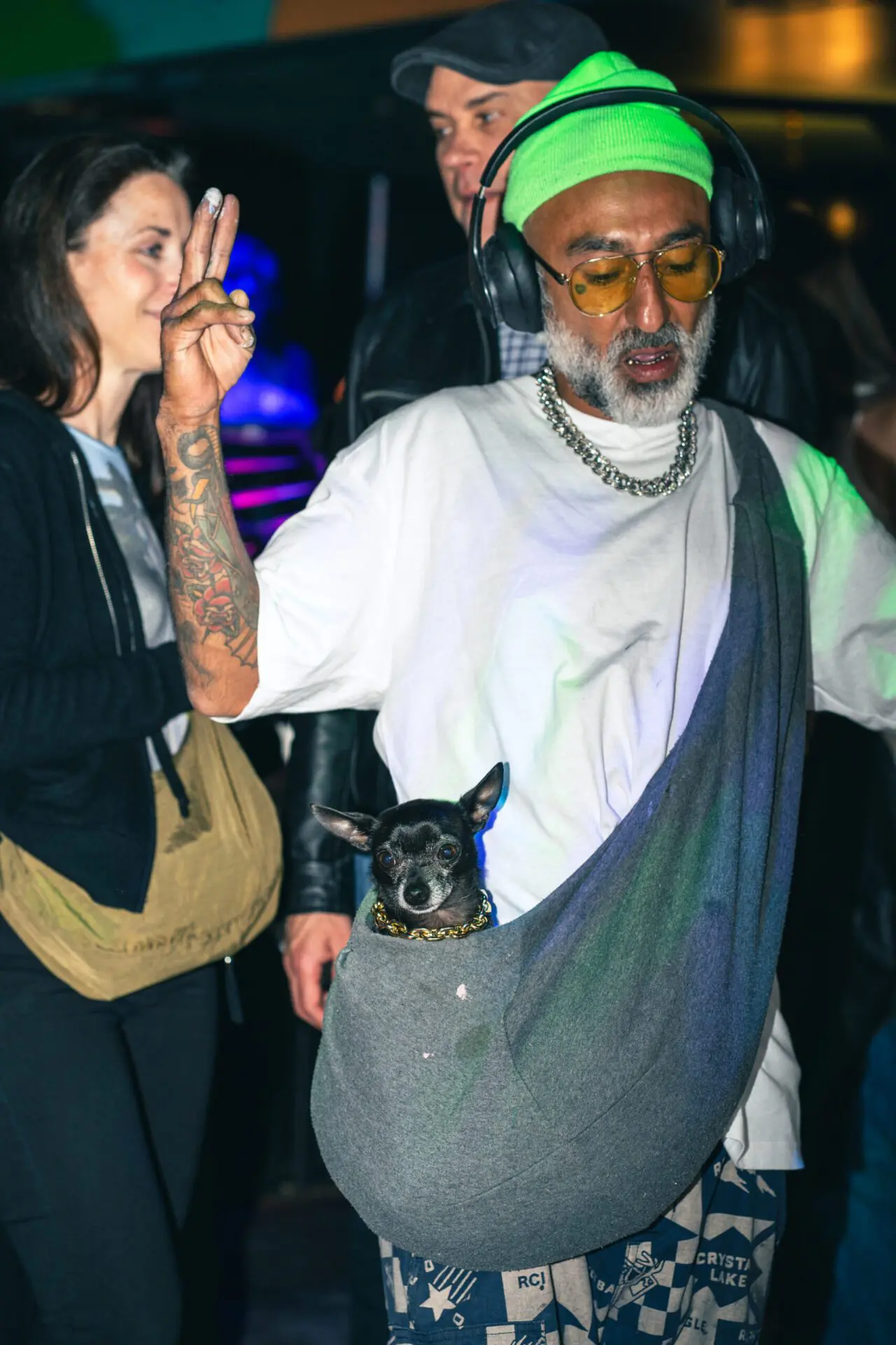 Man dancing with a small dog in a sling at the event.