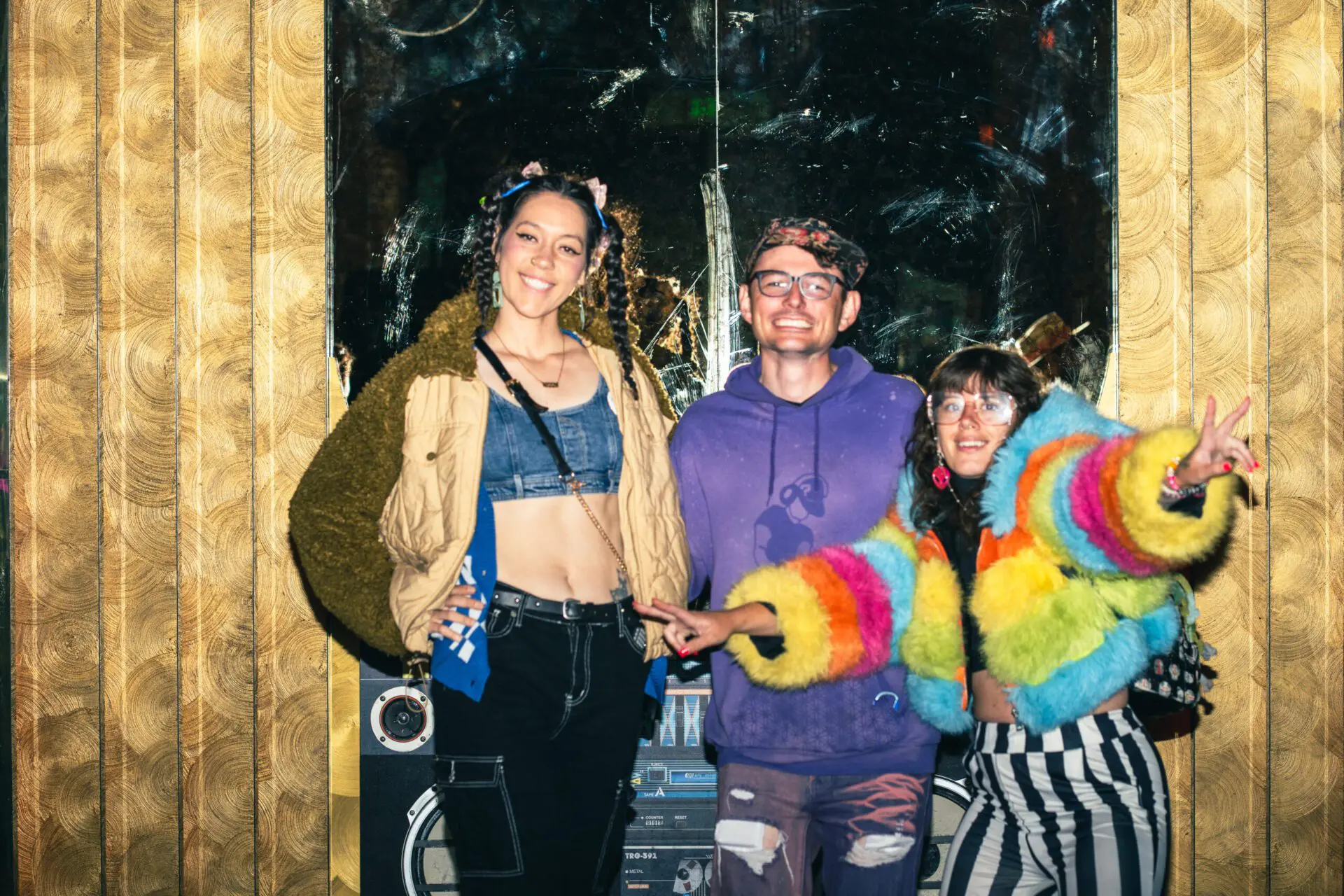 Three friends posing in front of an artist’s finished canvas.