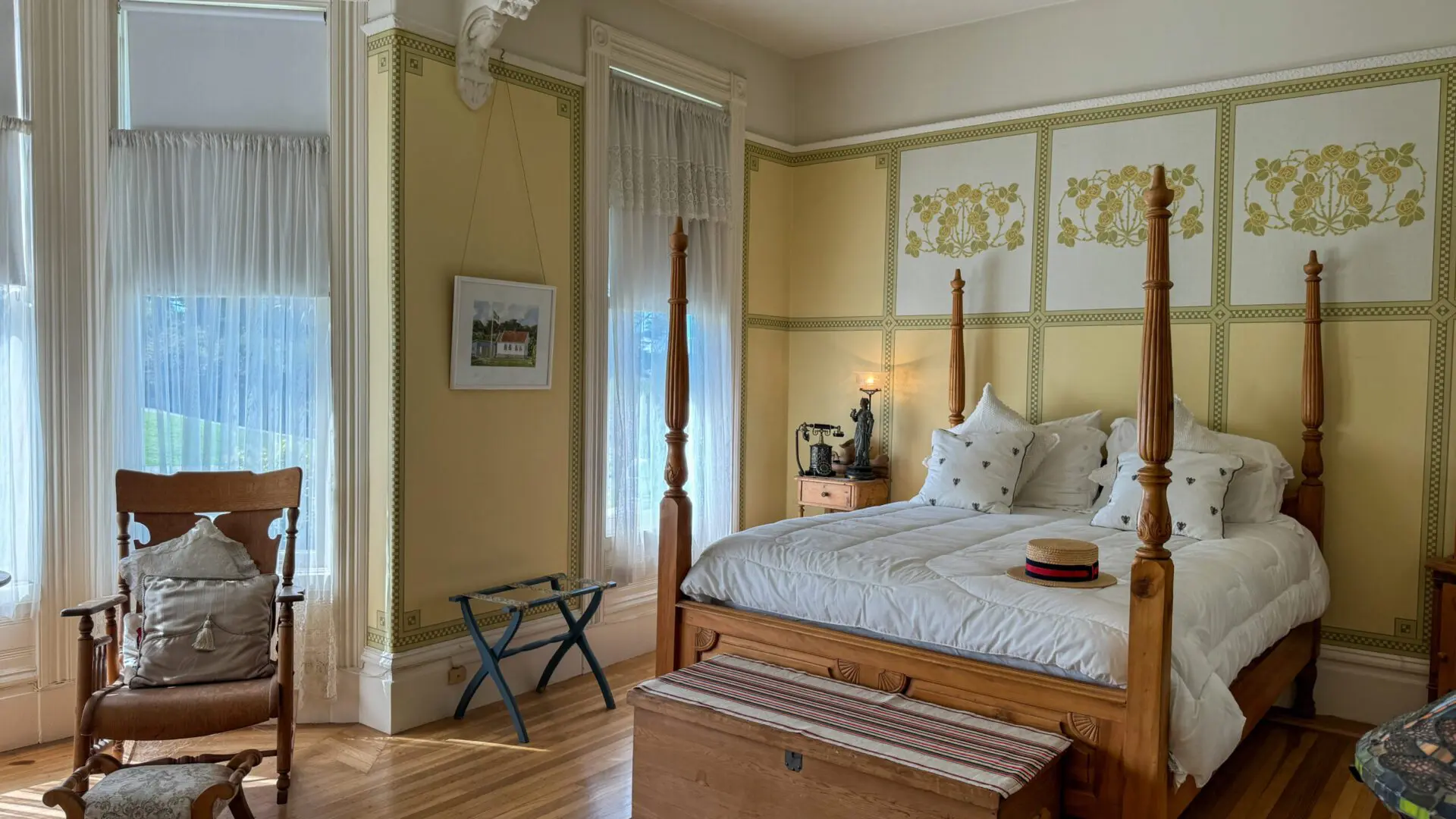 Bedroom inside a Victorian house with light streaming through tall windows