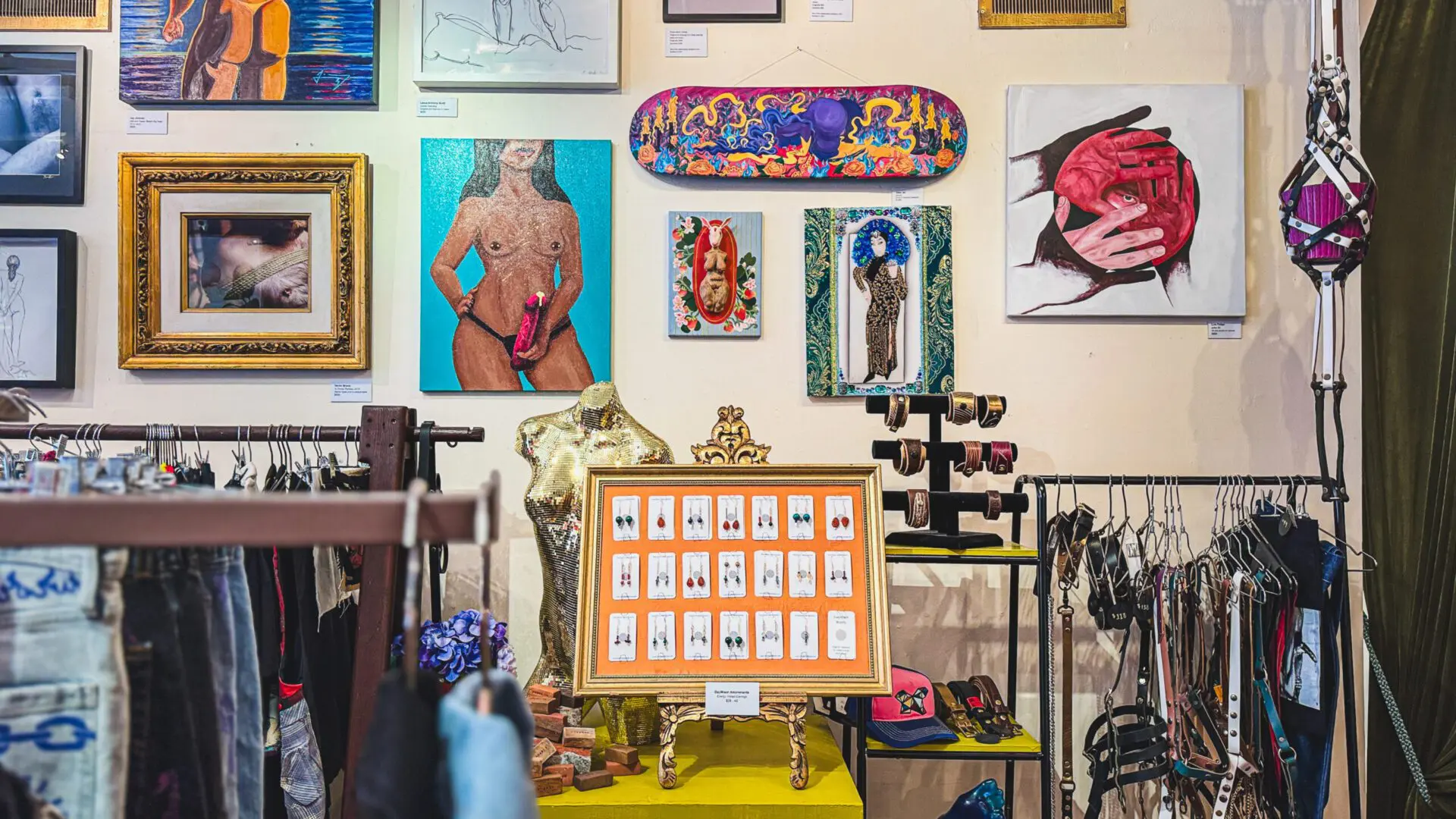 Walls filled with queer art, framed photos, and erotic artwork at Queer Arts Featured