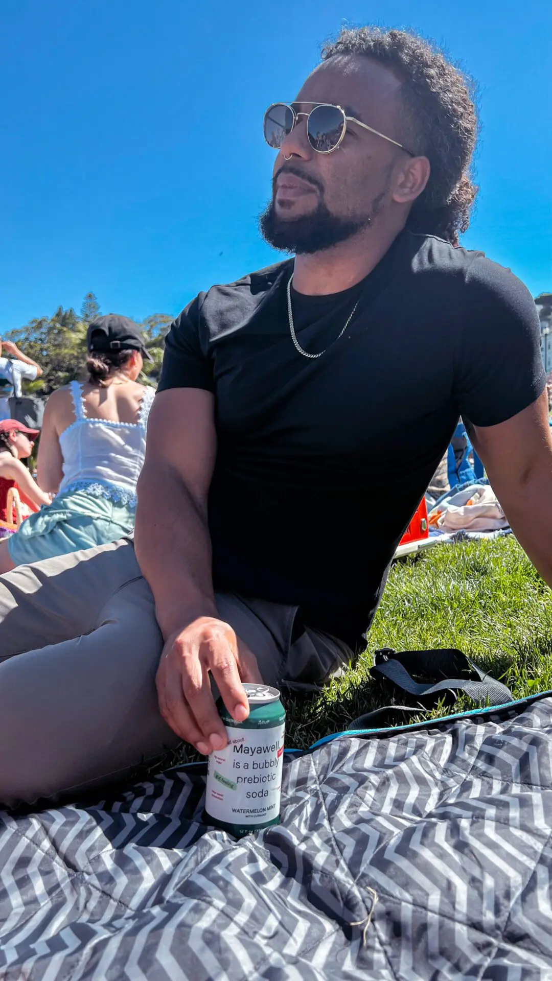 Close-up of friends lounging in the grass sharing drinks.