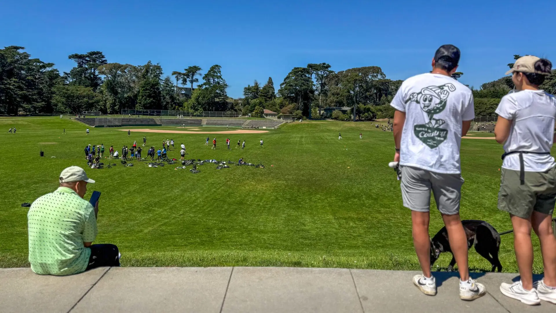 People sitting on the grass near a wide open meadow in Golden Gate Park