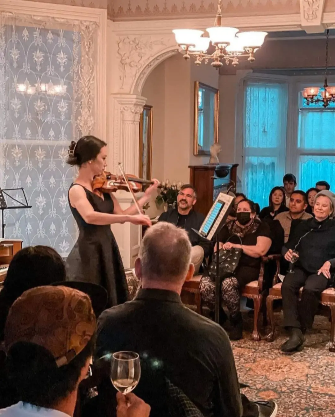 Intimate performance inside a historic Victorian parlor with an audience seated