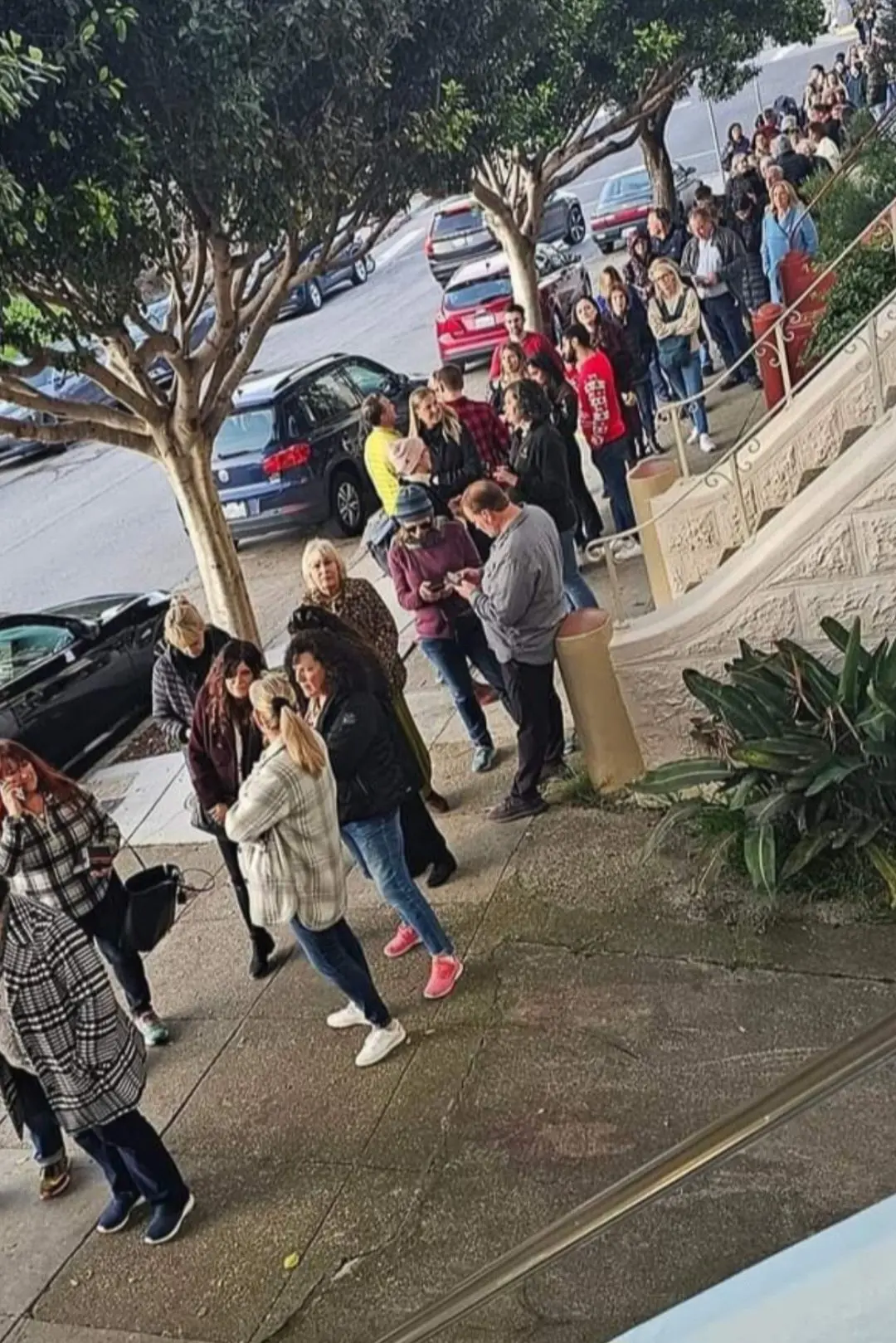 Line of visitors walking toward a historic Victorian home