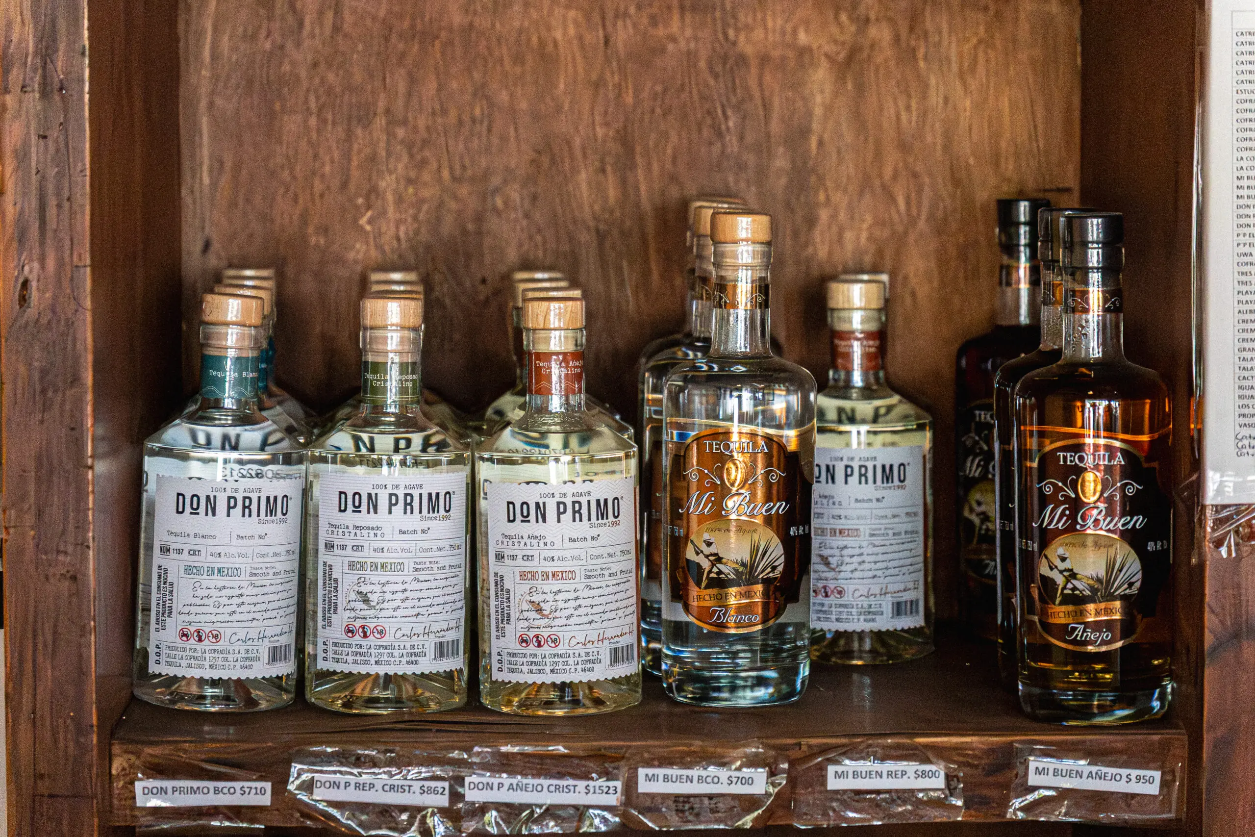 Row of whiskey bottles with detailed labels on a wooden shelf.