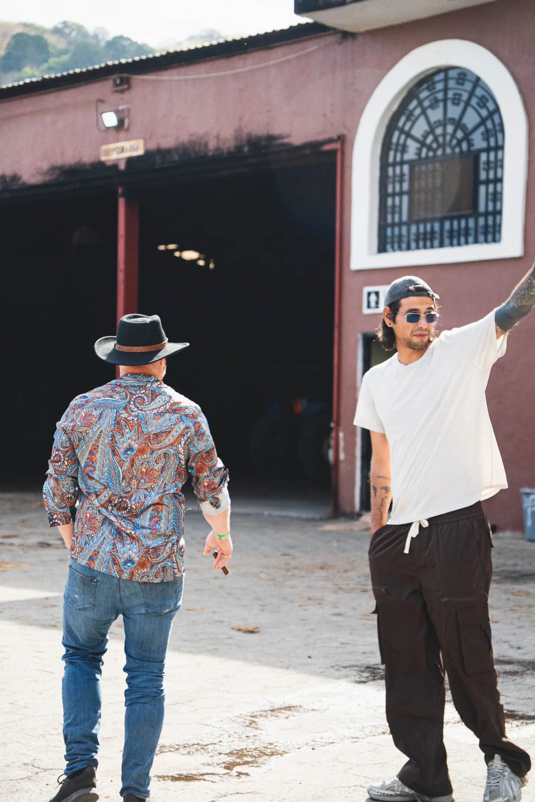 Two men standing outdoors, one pointing ahead.