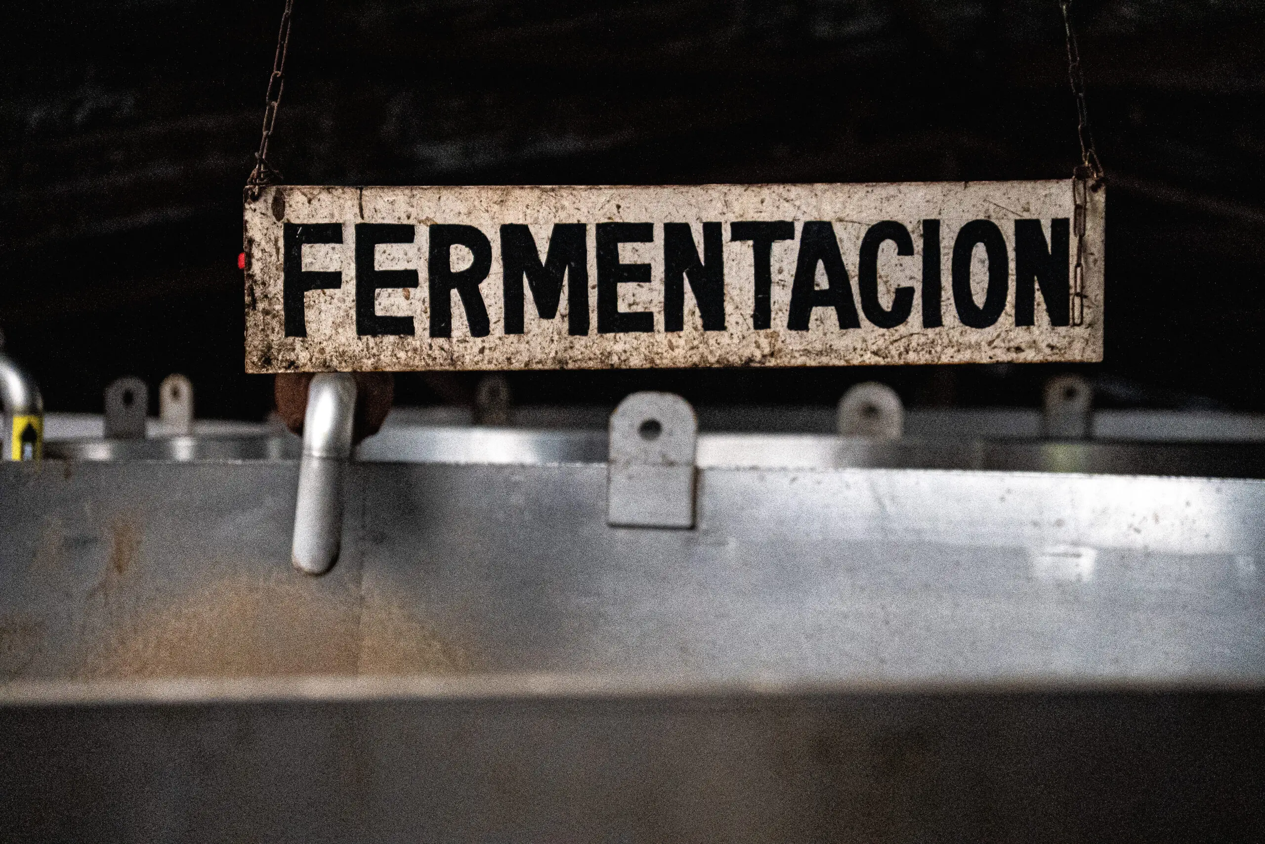 Old metal sign reading 'FERMENTACION' in a rustic setting.