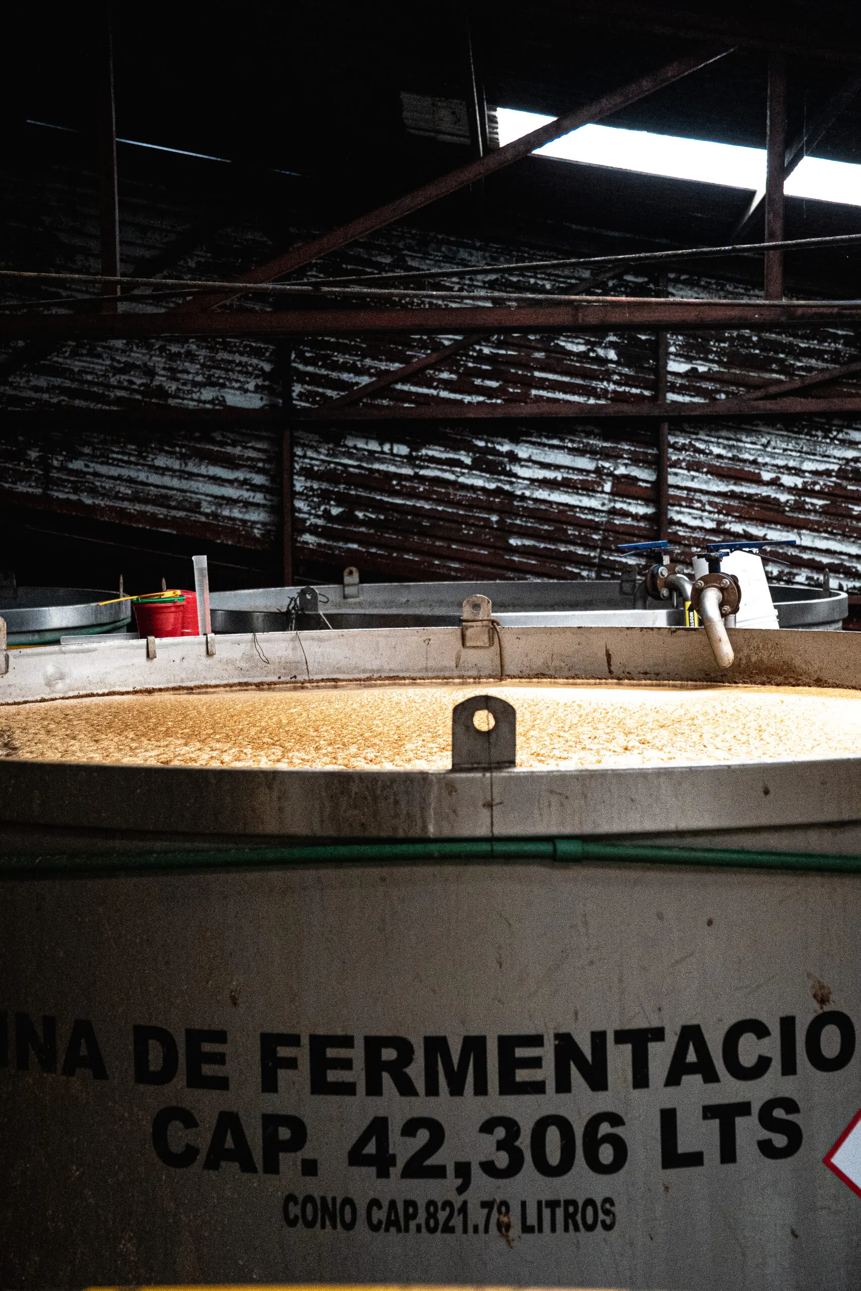 Large fermentation tank in a brewery with bubbling liquid inside.