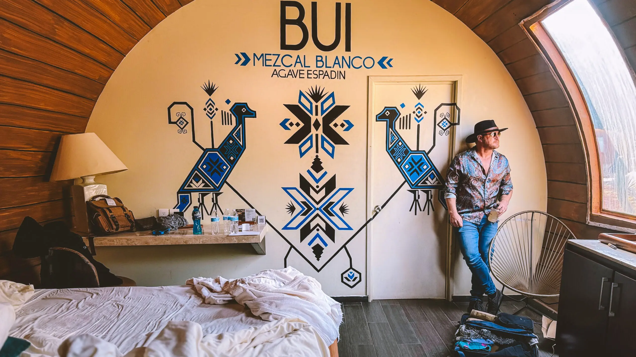 Wall mural art featuring mezcal motifs with a man leaning against the wall.
