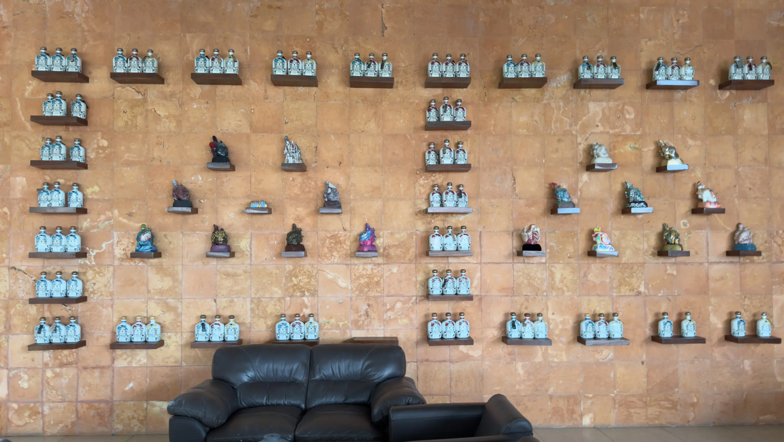 Wall display of decorative animal figurines and pottery above a black sofa.