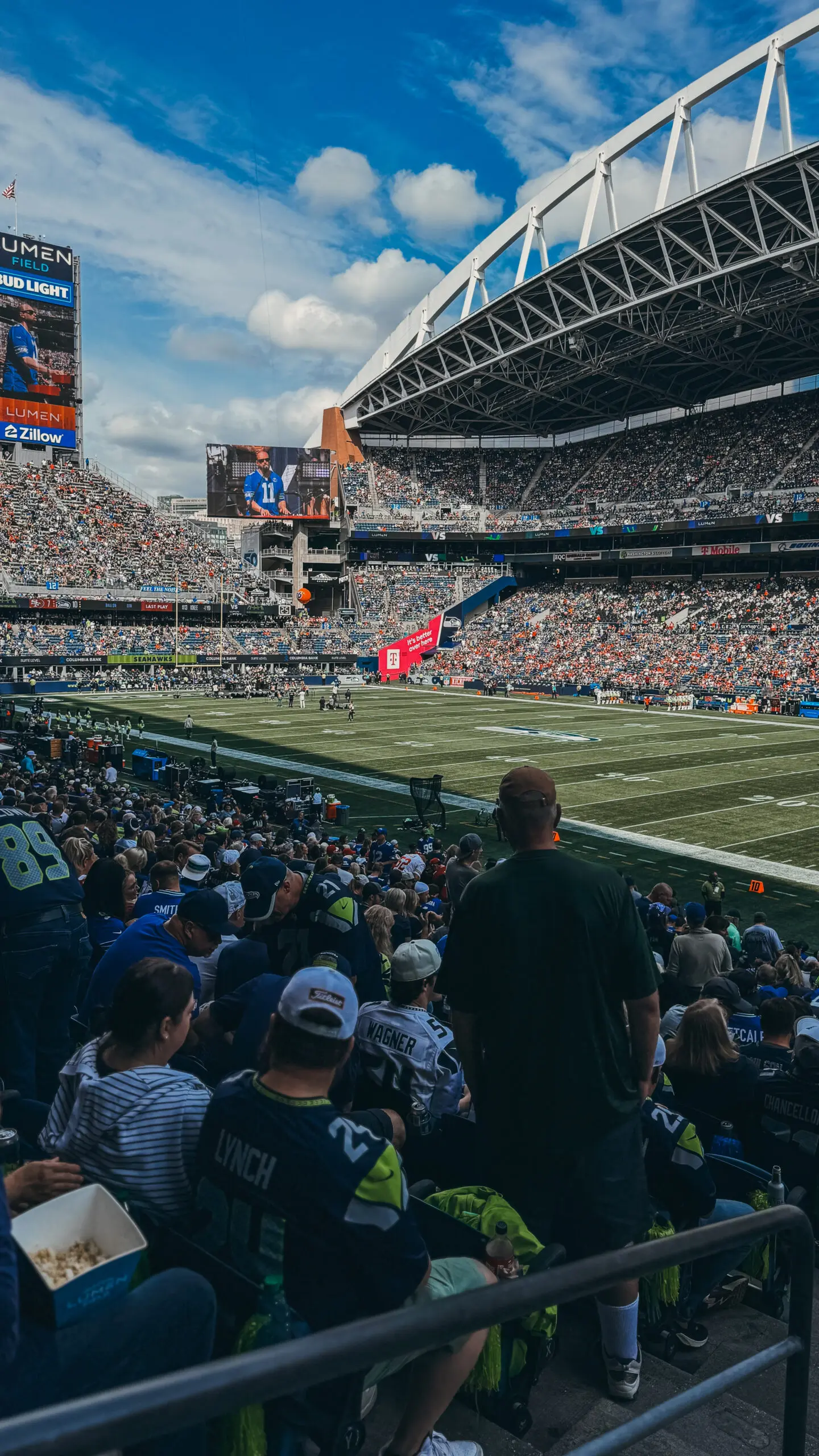 Crowded stadium during a football game with fans and players on the field.