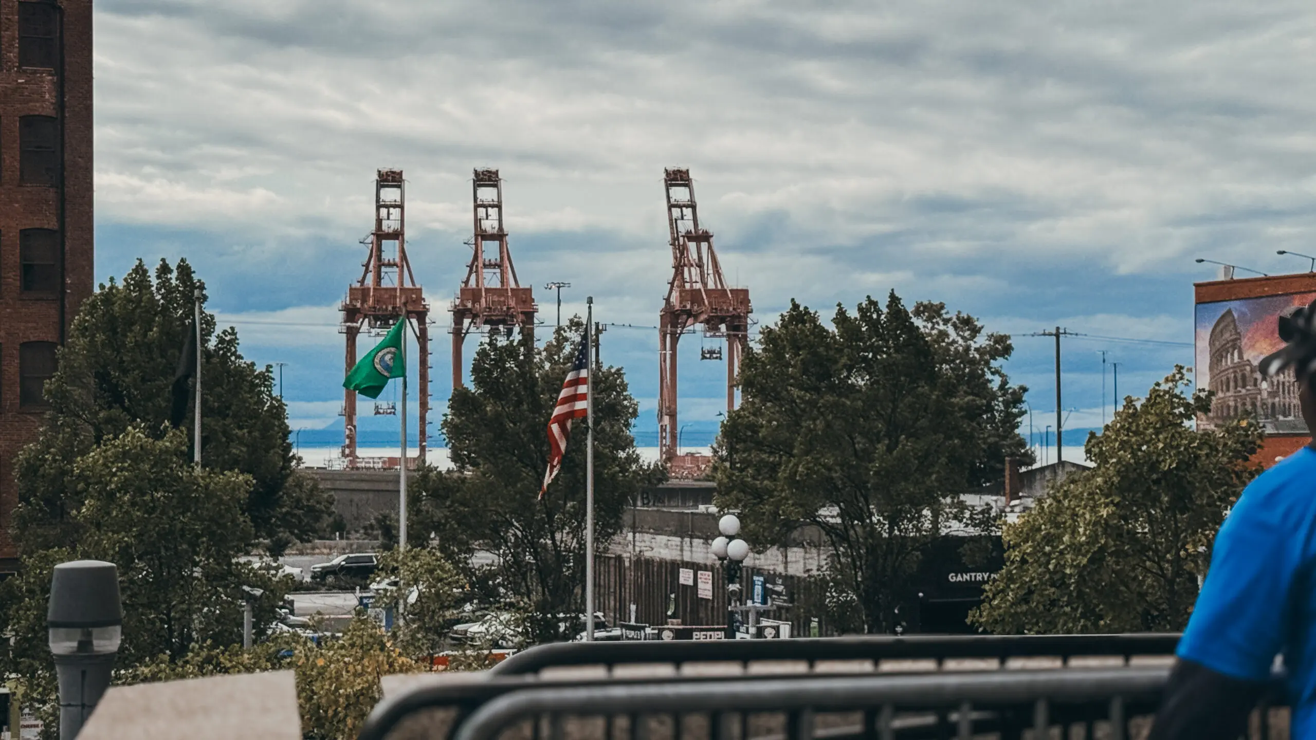 Industrial cranes at a busy port with an American flag flying.