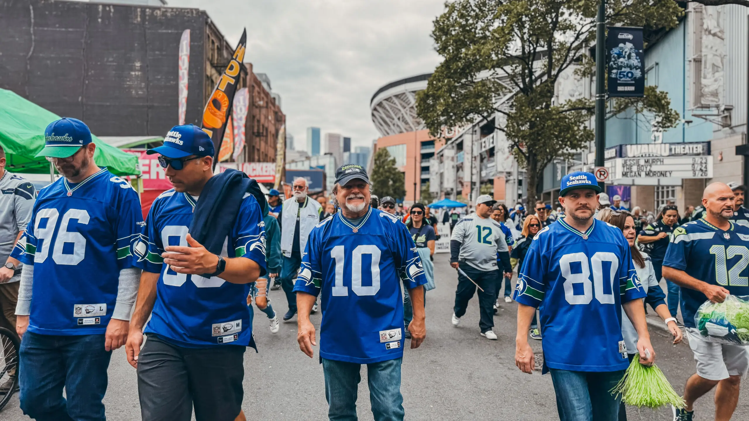 Football fans in blue jerseys walking down a street.