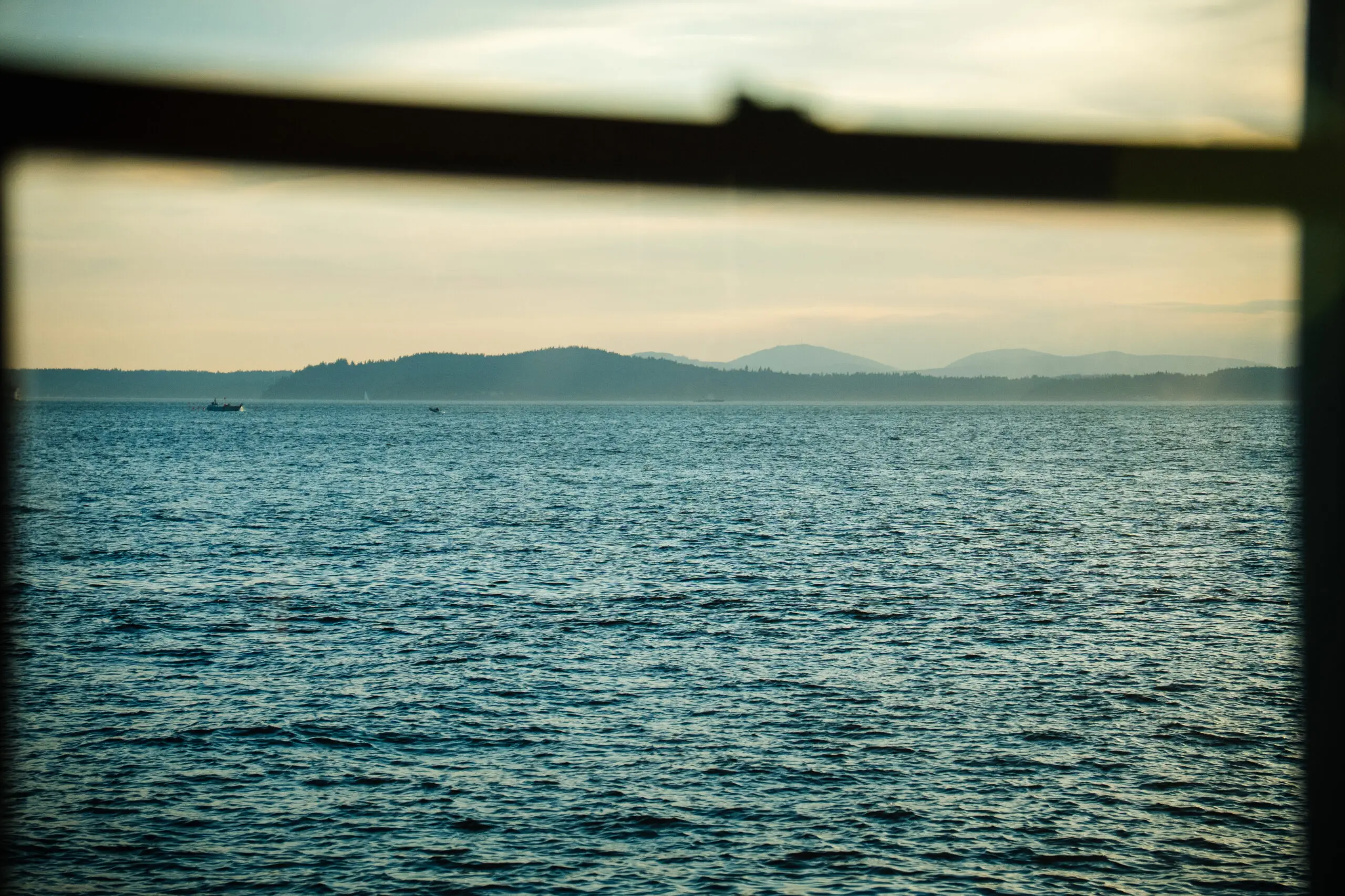 View of a calm sea with distant hills under a soft sky.