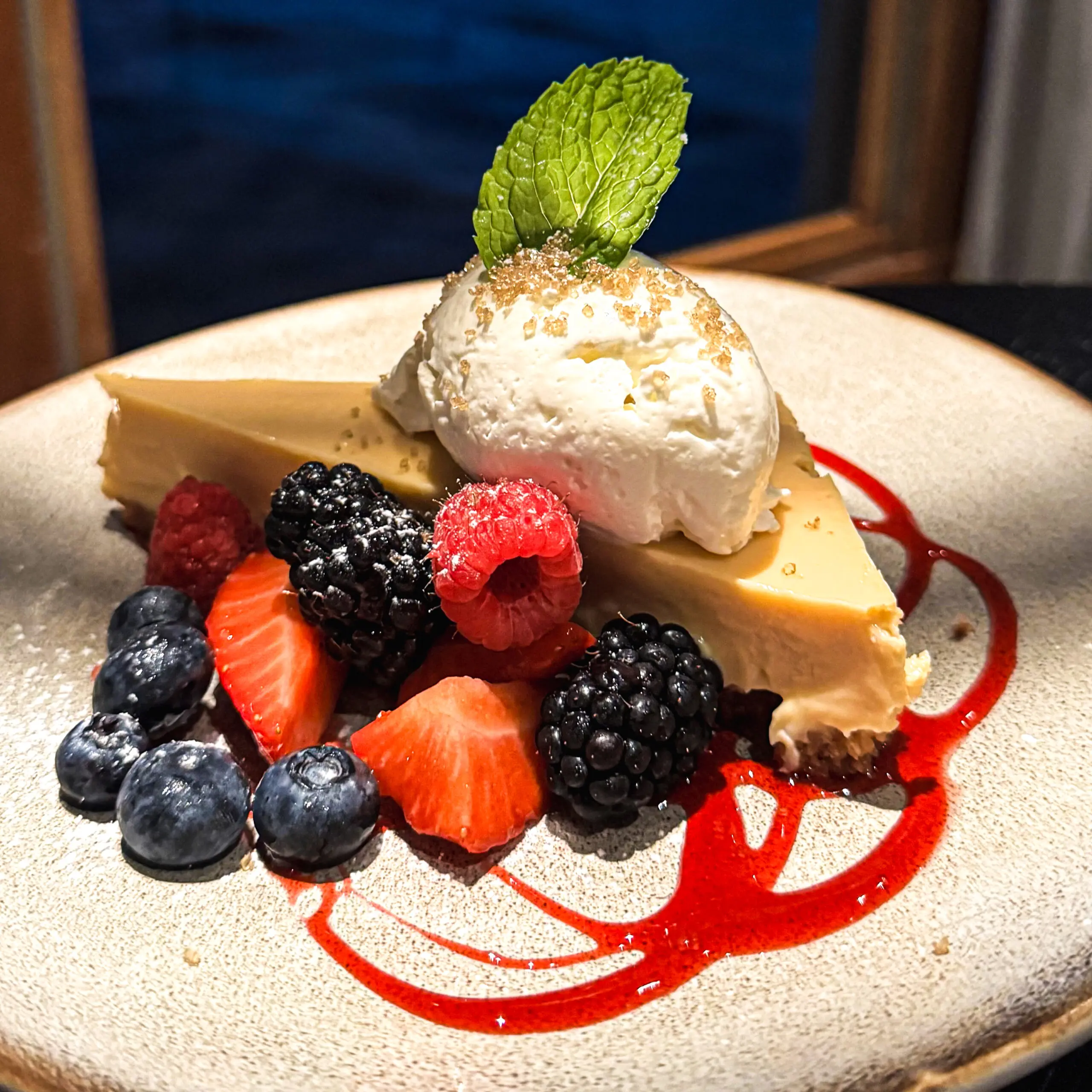 Cheesecake slice with ice cream and fresh berries on a plate.