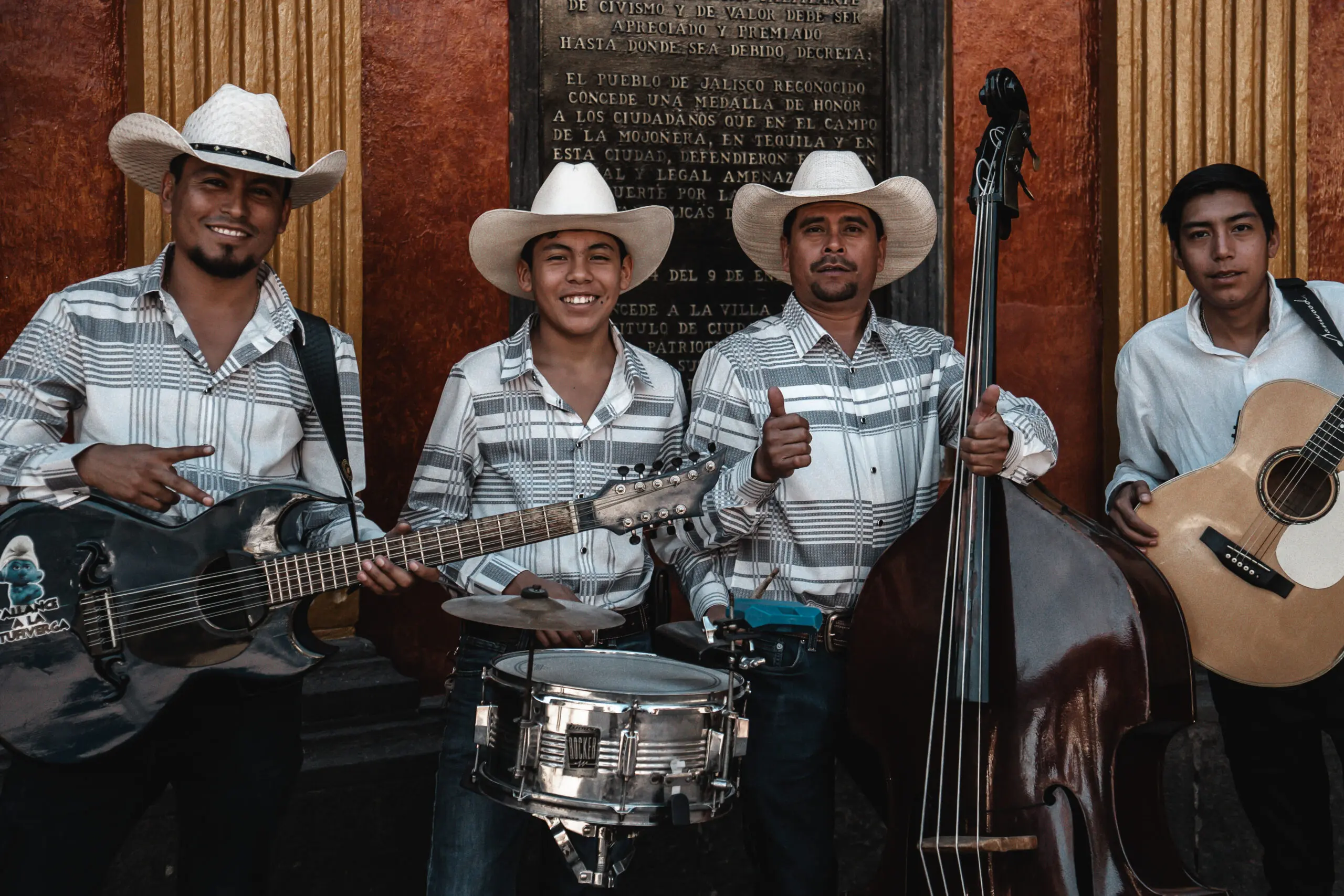 Three musicians in cowboy hats playing traditional instruments and smiling.