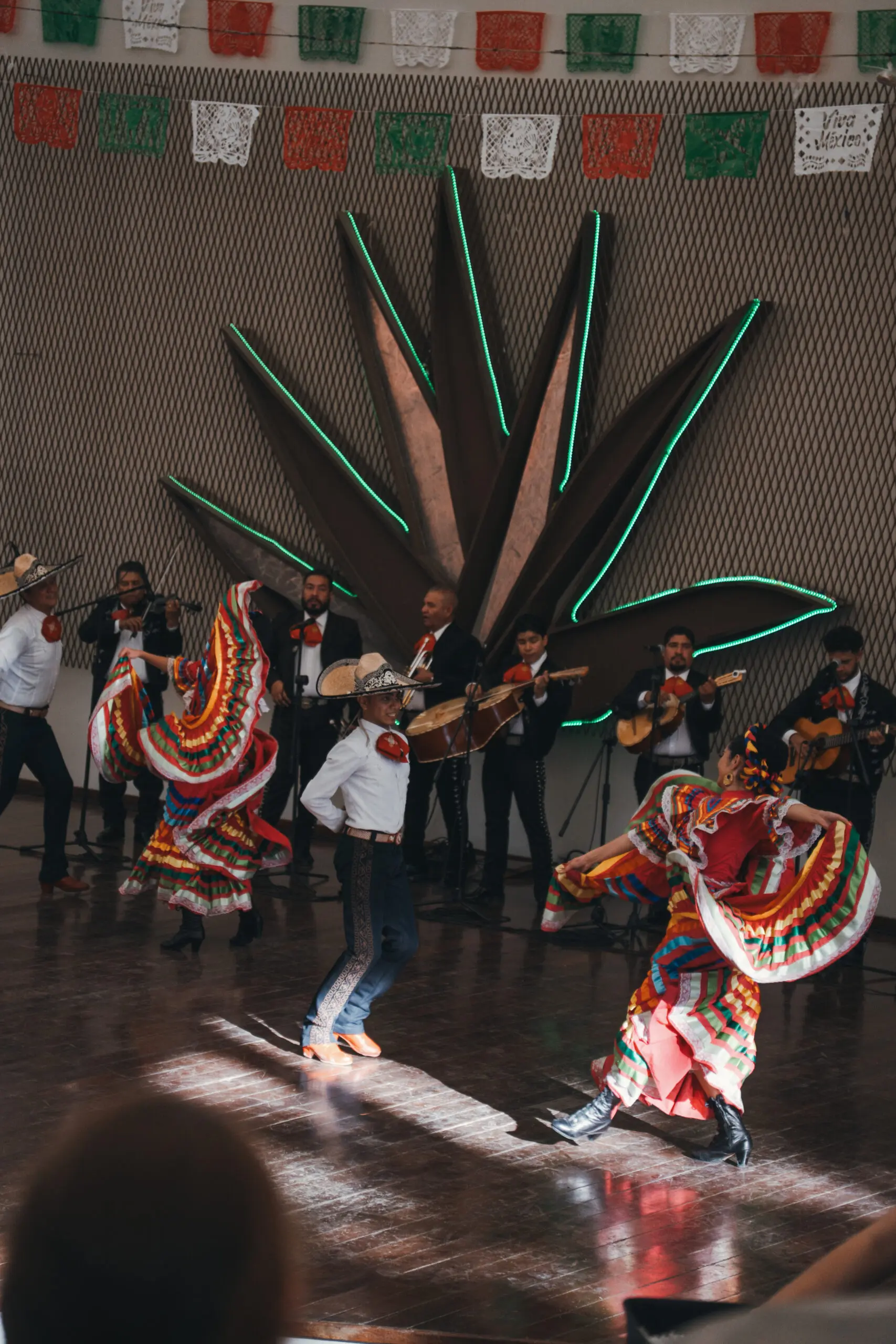 Dancers in colorful traditional attire perform with musicians in the background.