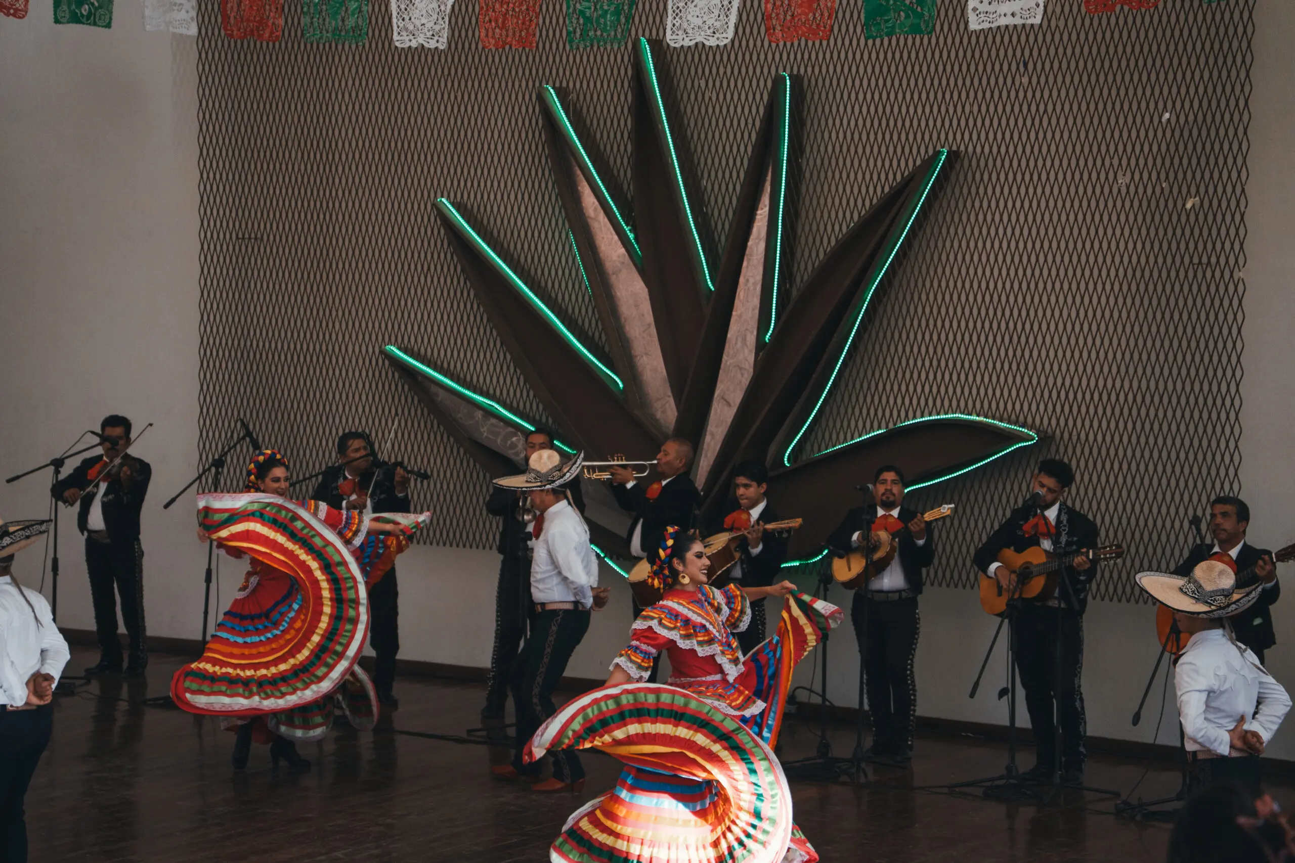 Mexican folkloric dancers performing with vibrant costumes and musicians in the background.
