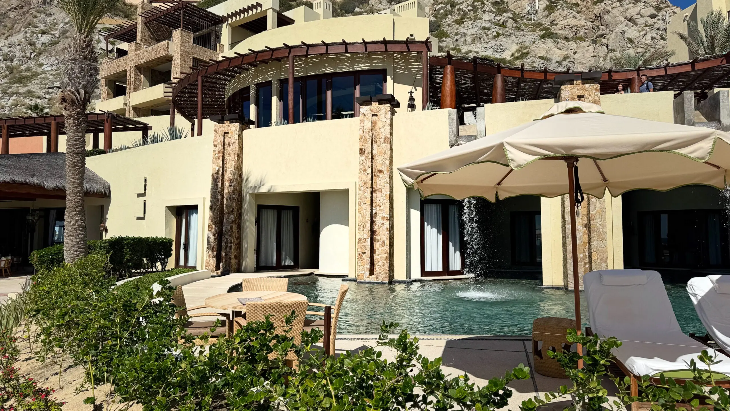 Luxurious villa with pool and mountain backdrop under clear sky.