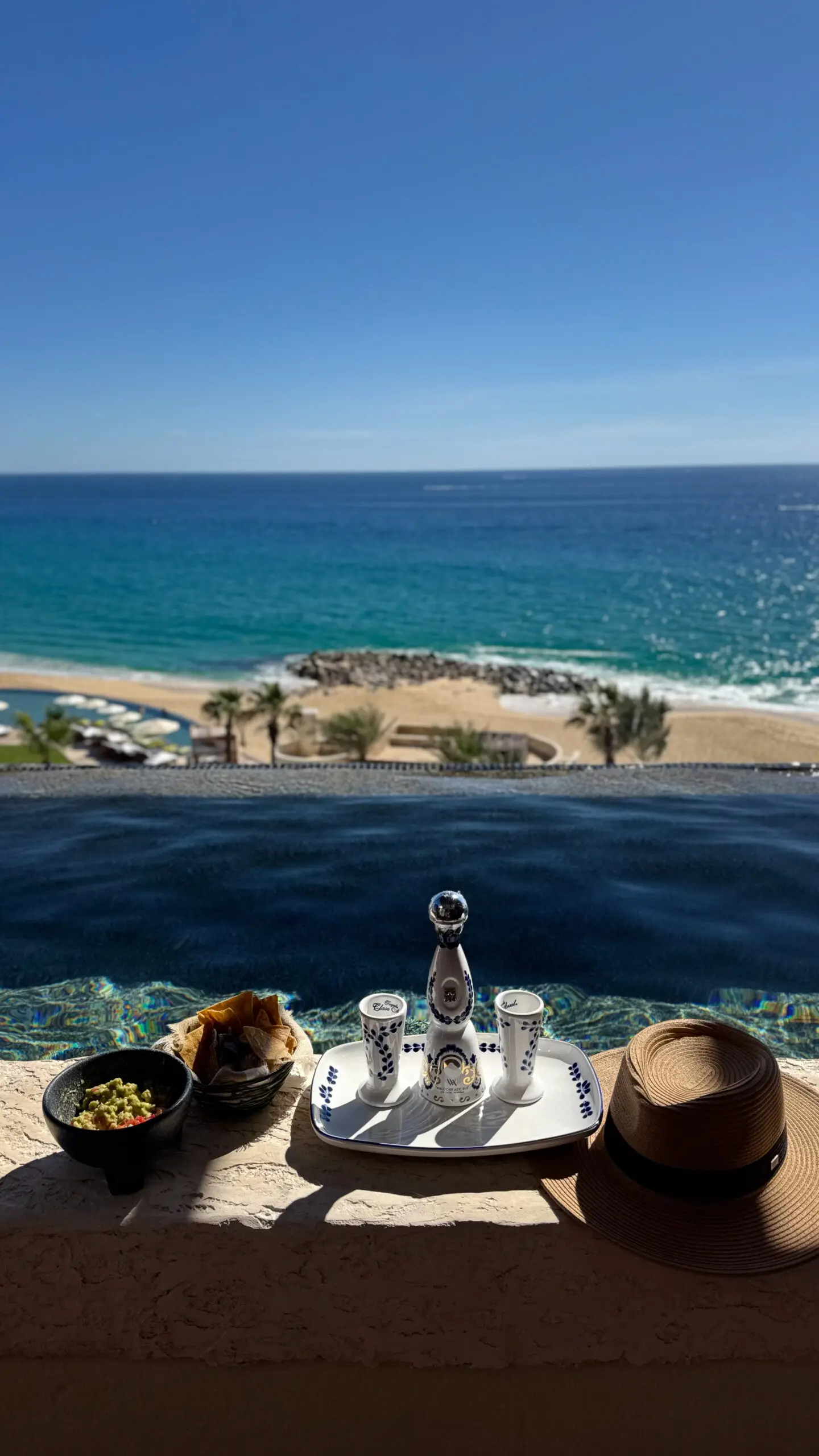 Scenic ocean view with beach and infinity pool overlooking a breakfast setup.