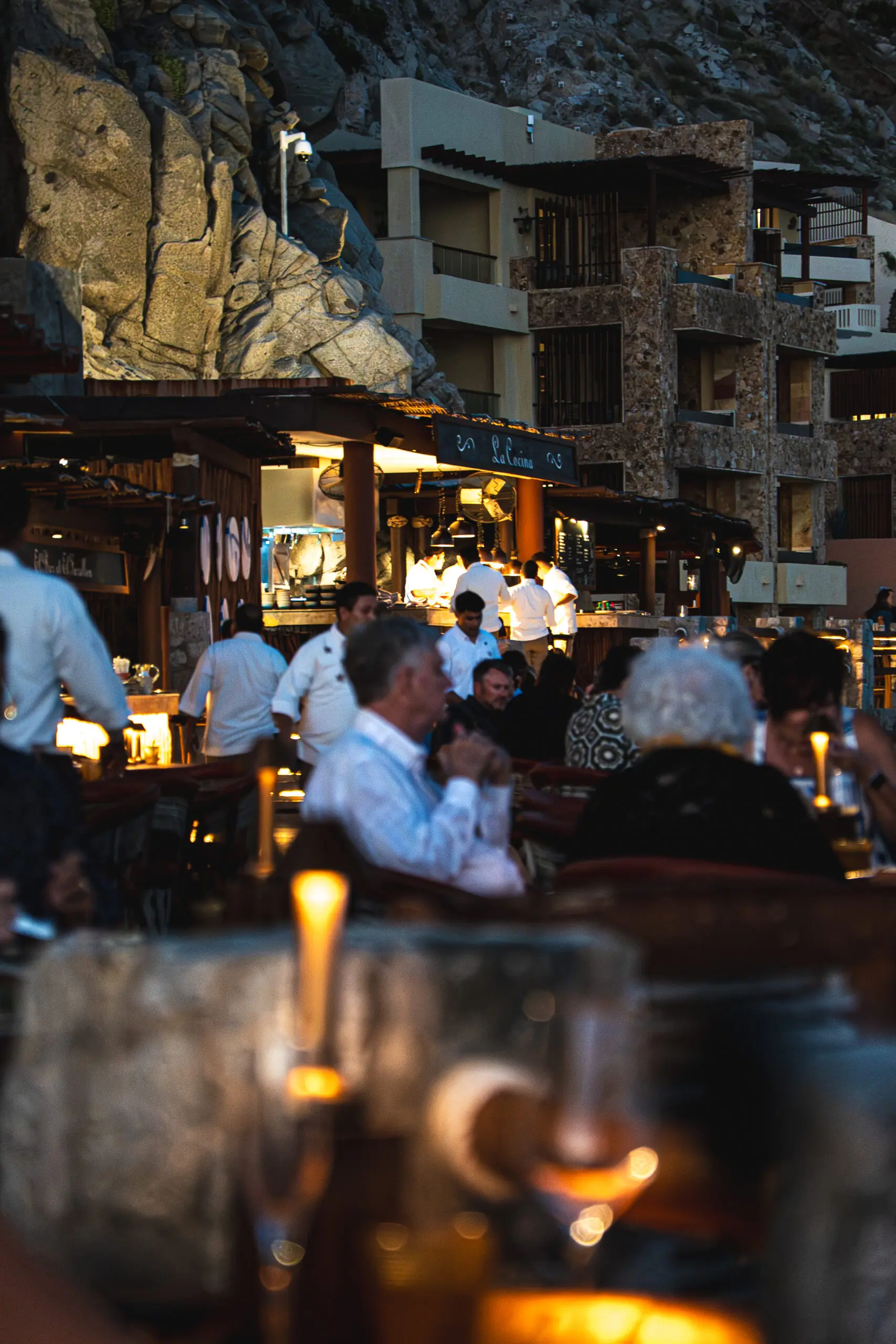 Cozy outdoor restaurant scene with patrons enjoying dinner under warm lighting.