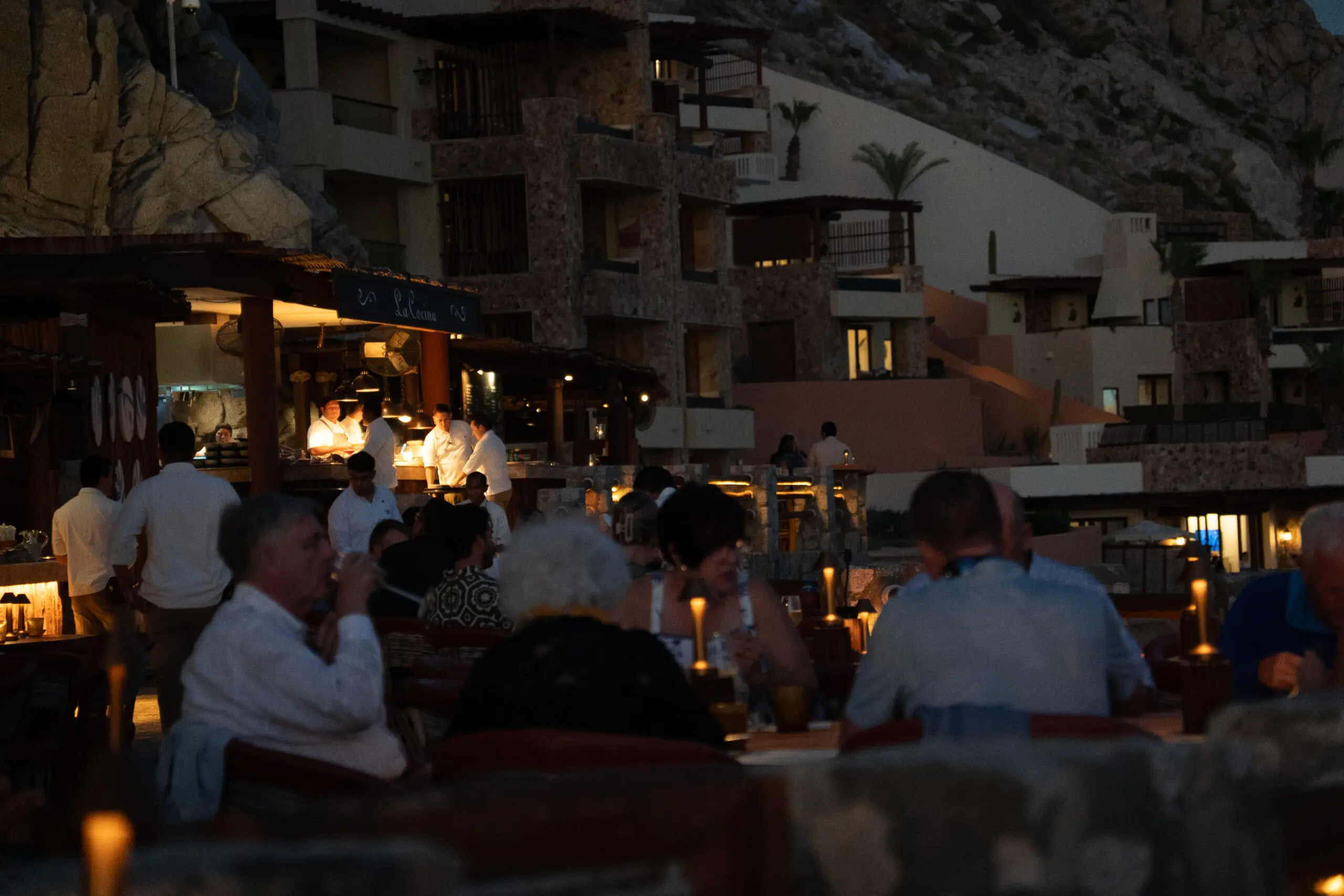 People dining outdoors at a cozy, dimly lit restaurant in the evening.
