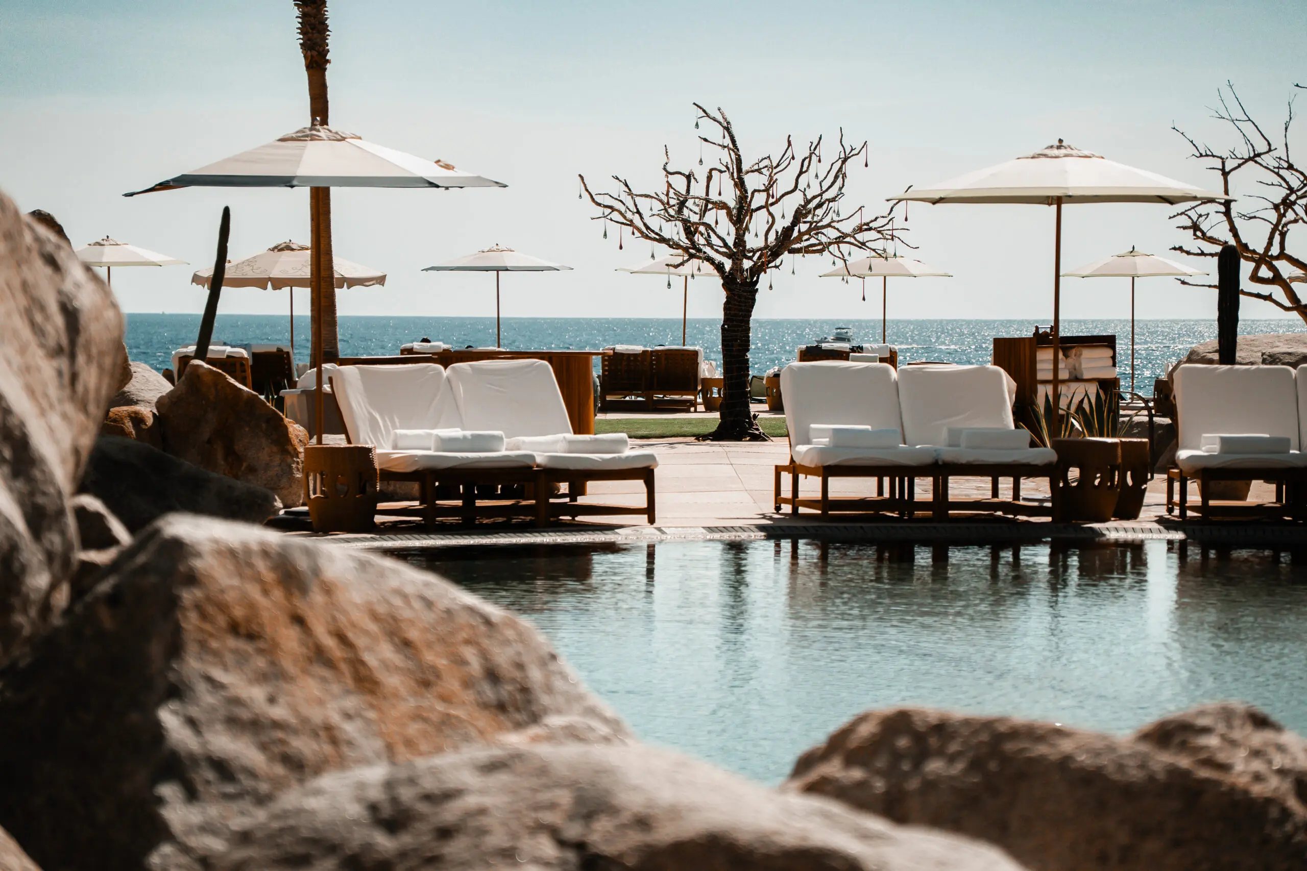 Luxurious poolside lounge with ocean view and white umbrellas.