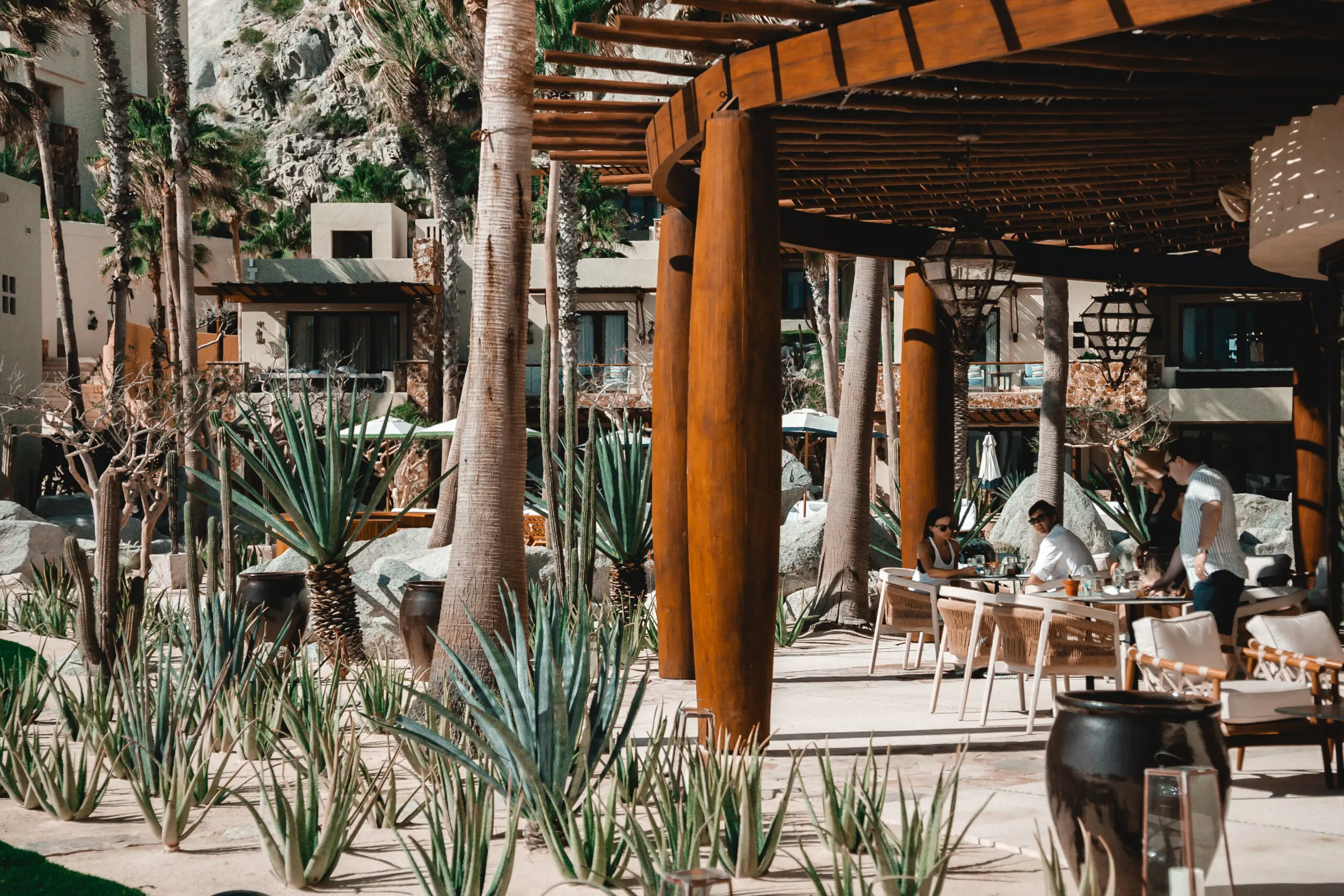 Outdoor seating area with wooden columns and lush greenery.