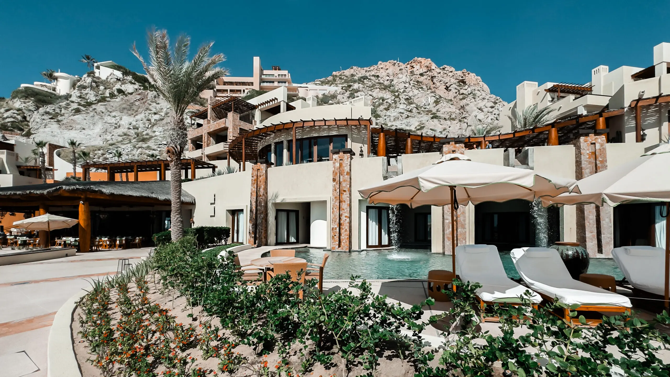Modern resort blending with rocky hillside under clear sky.