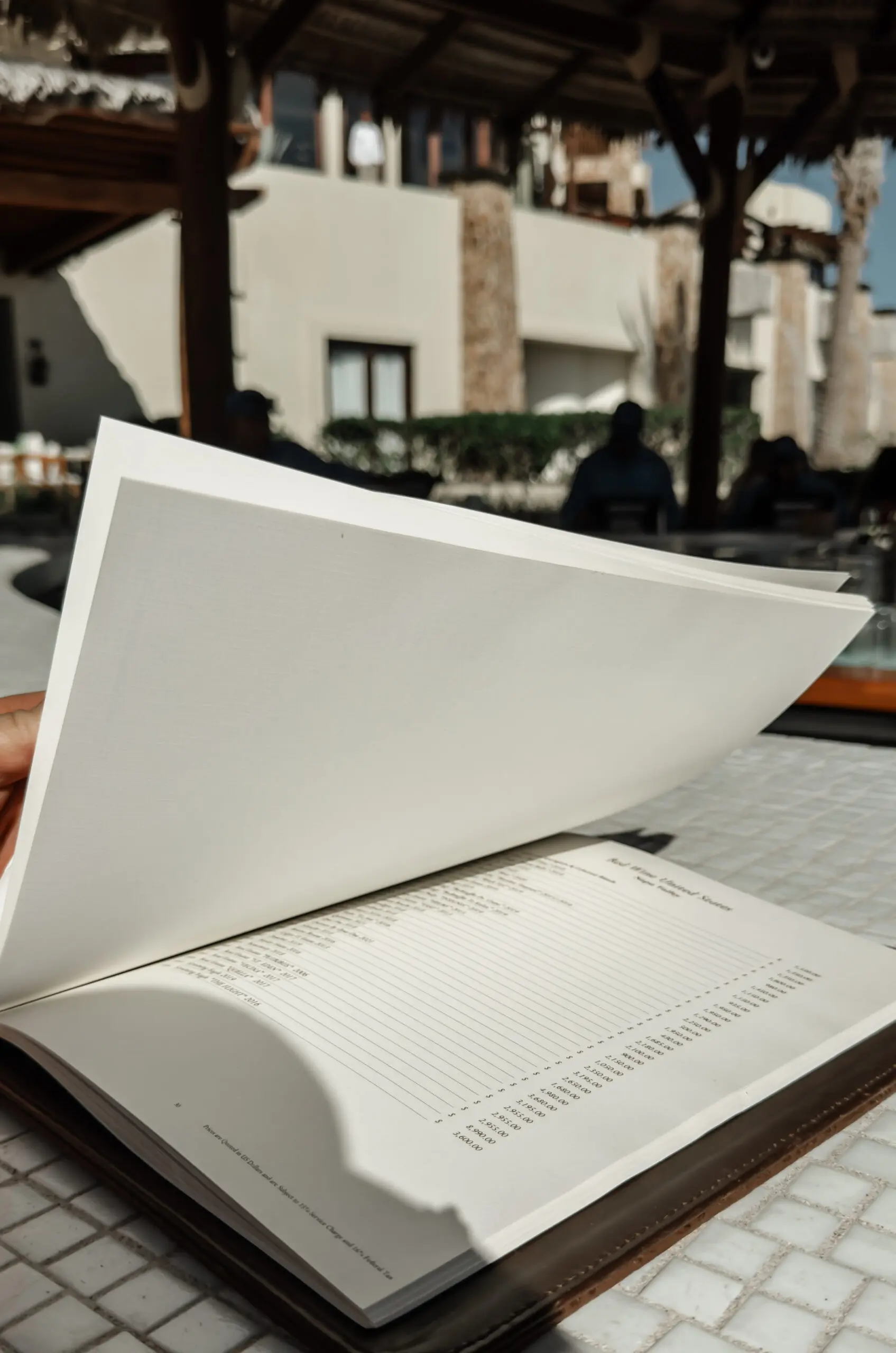 A close-up of a book with a page being flipped outdoors.