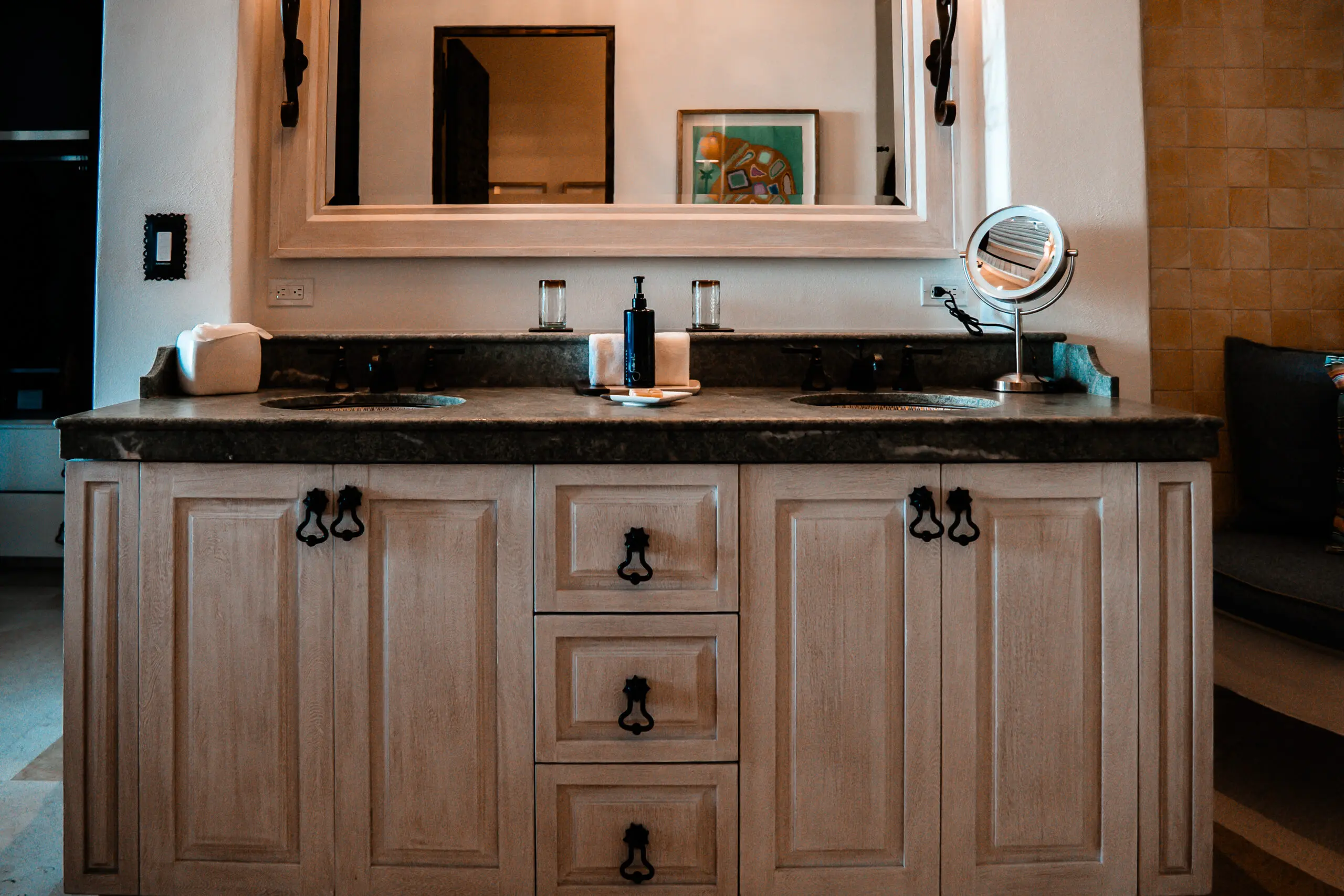 Elegant bathroom vanity with wooden cabinets and black countertop.