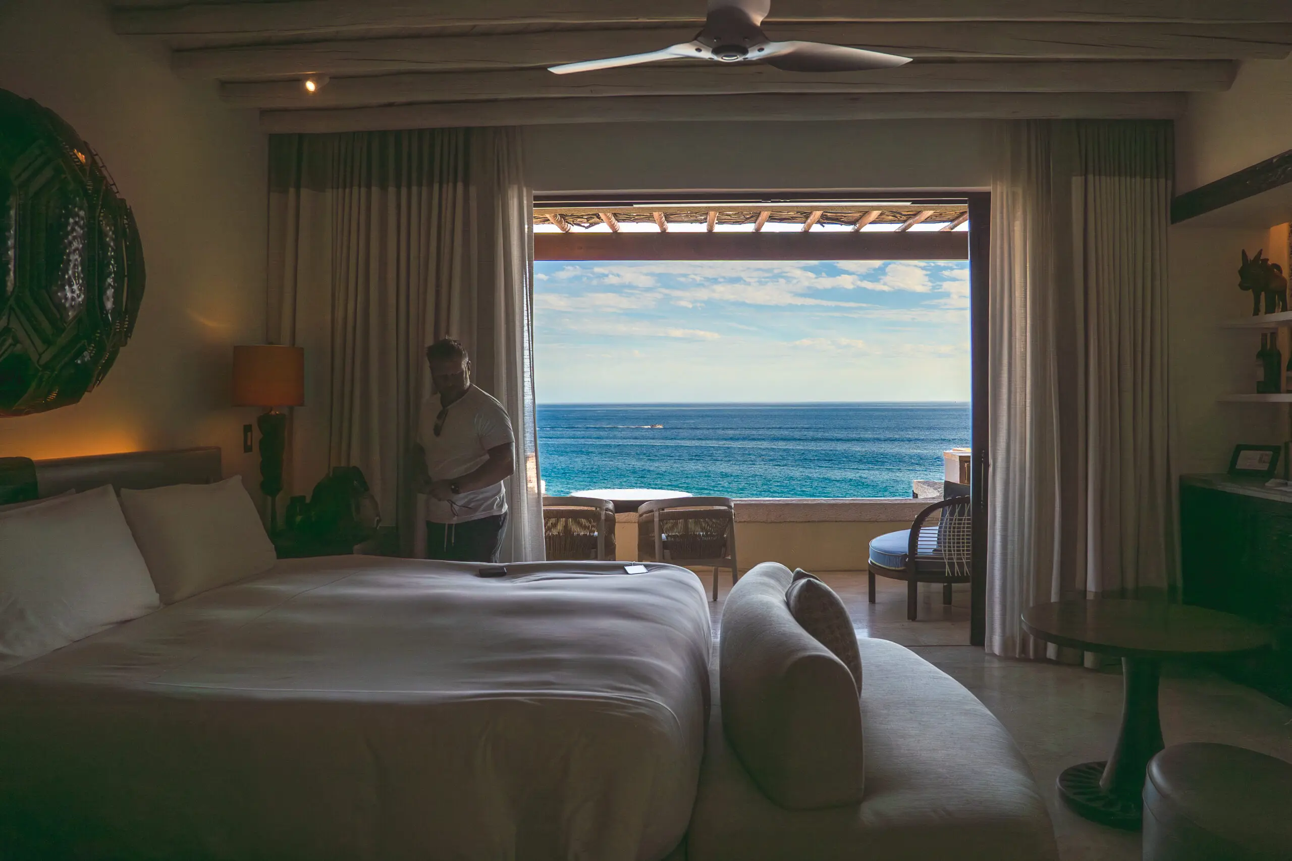 A cozy bedroom with a view of the ocean through large sliding doors.
