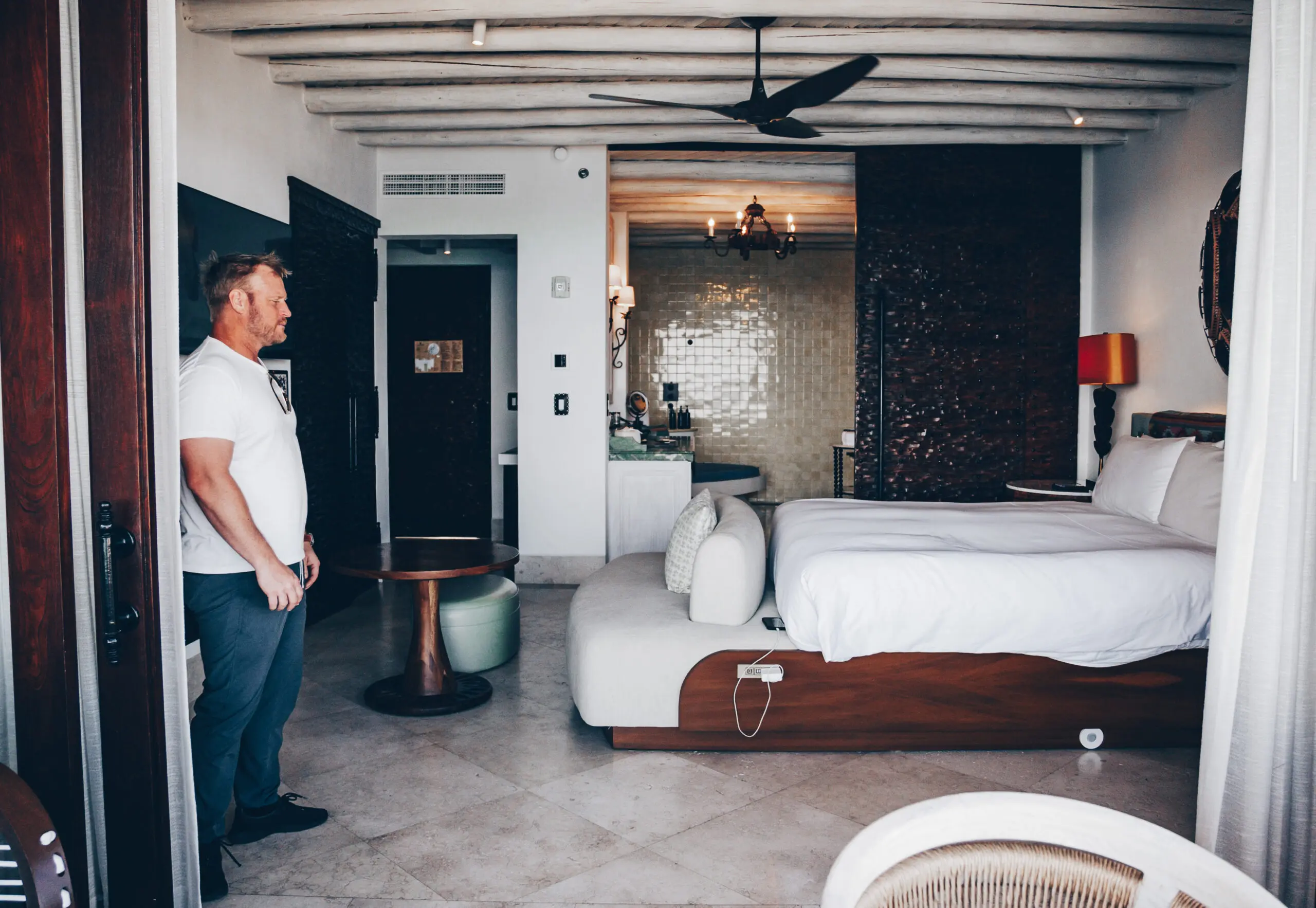 Man standing in a modern, stylish bedroom with wooden accents.