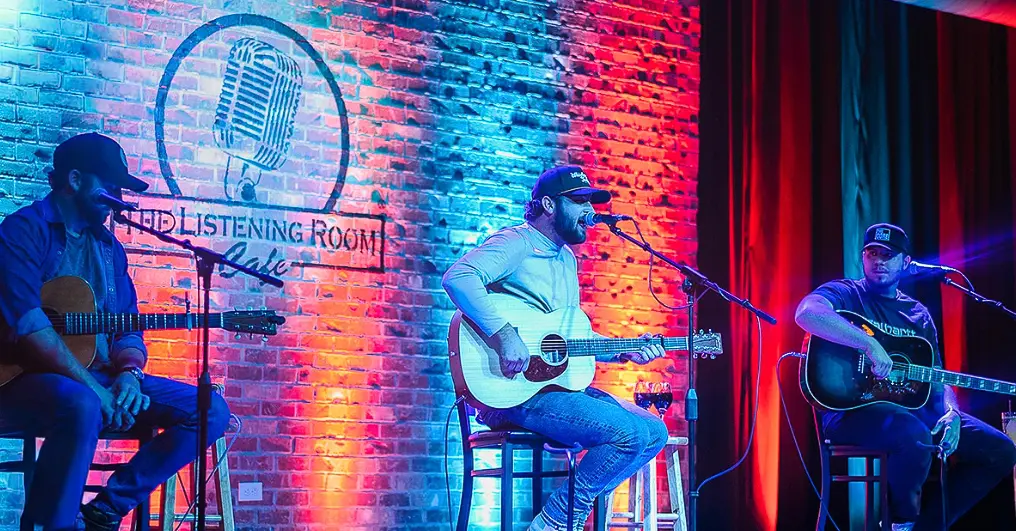 woman with a bob haircut holding a camera up to her face with a light in the background