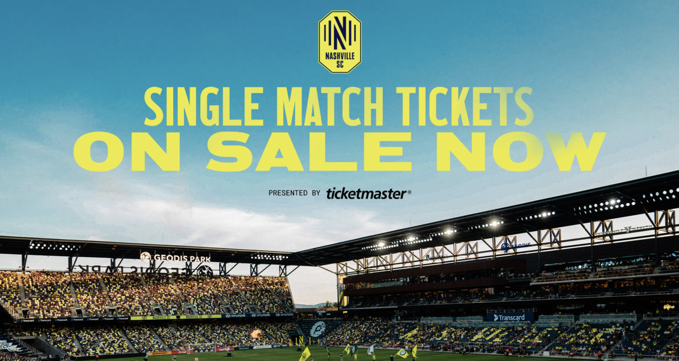 woman with a bob haircut holding a camera up to her face with a light in the background