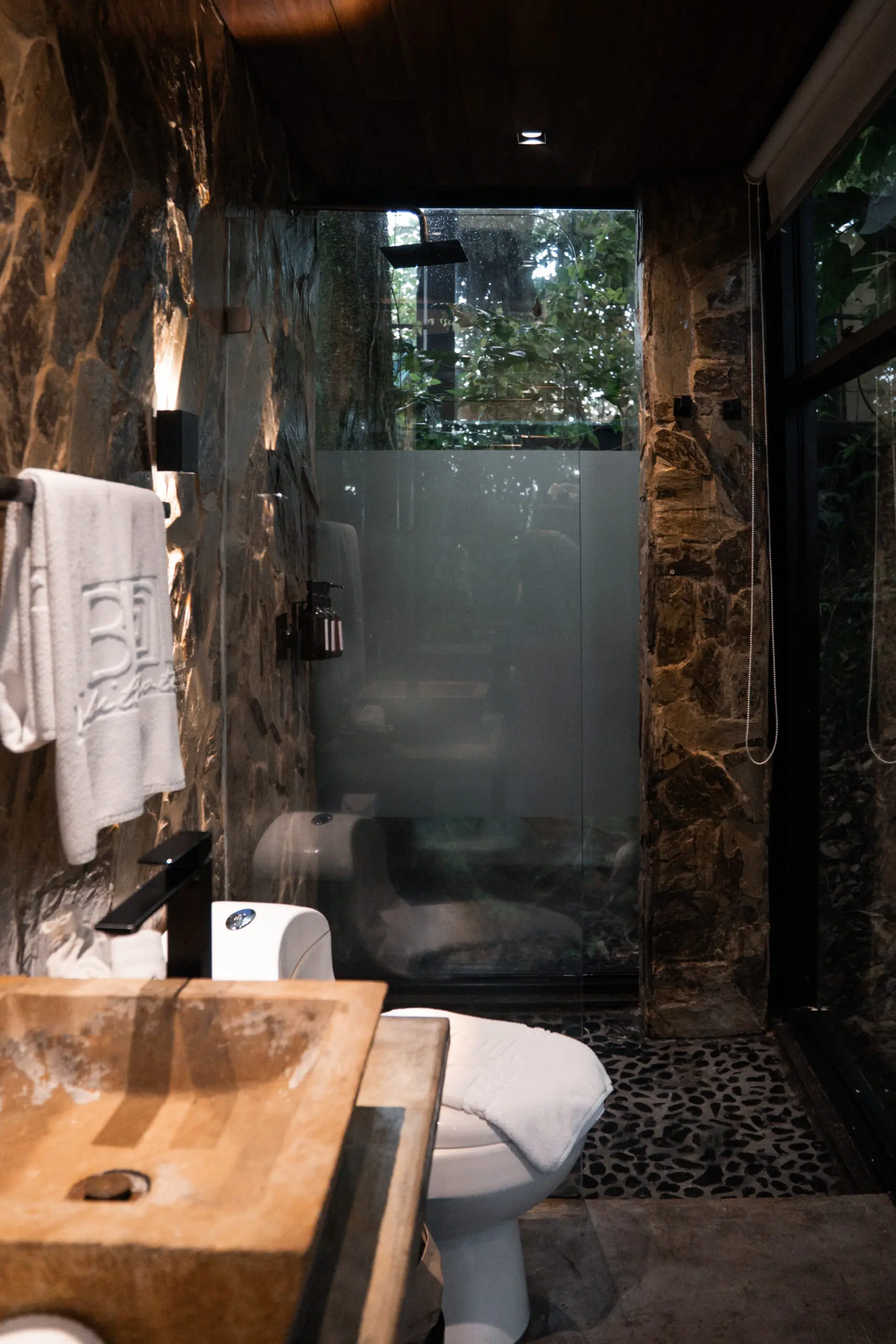 Cozy bathroom with stone walls and frosted glass shower.