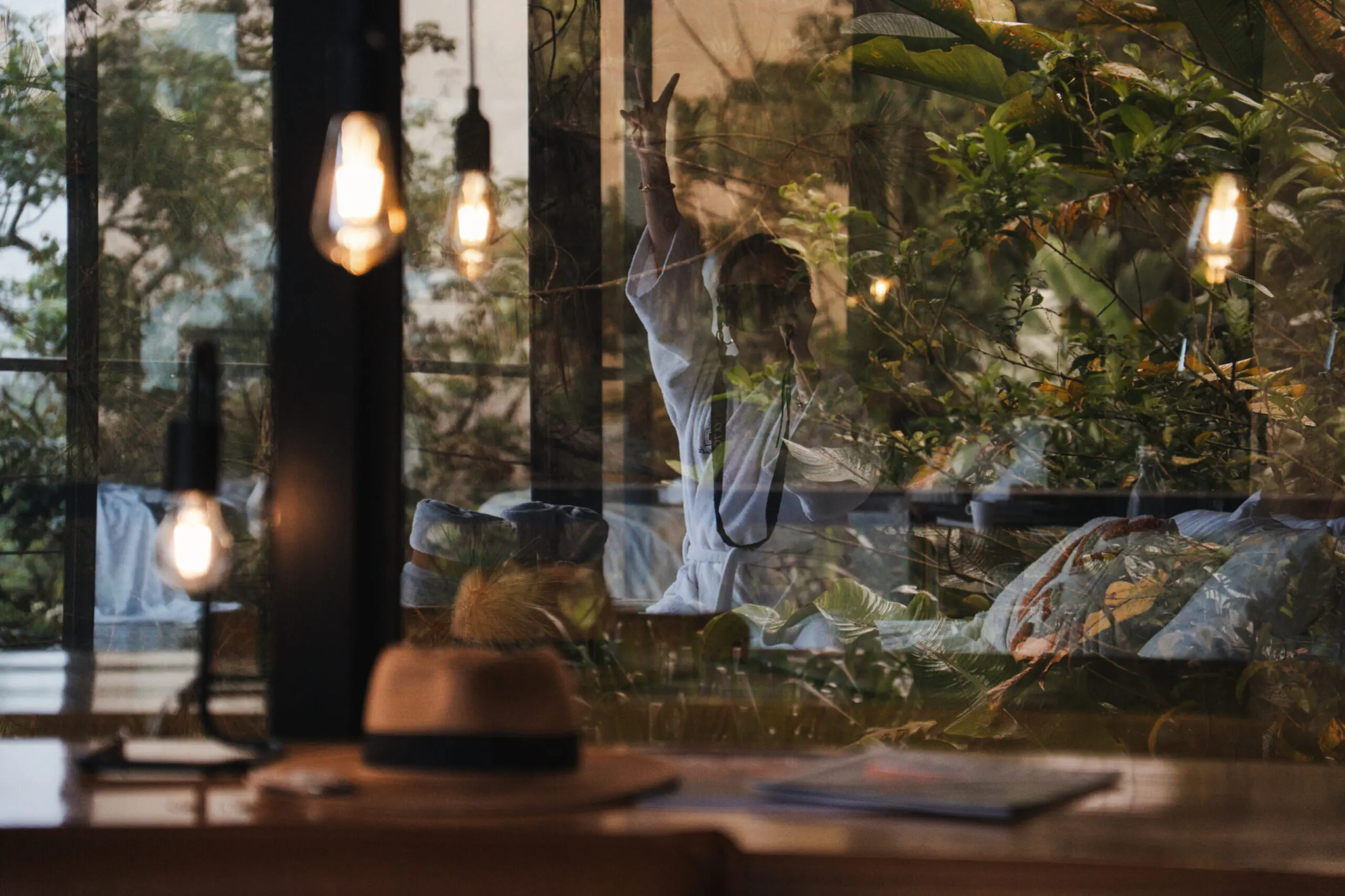 Person raising hand inside a cozy cafe with hanging lights and plants.