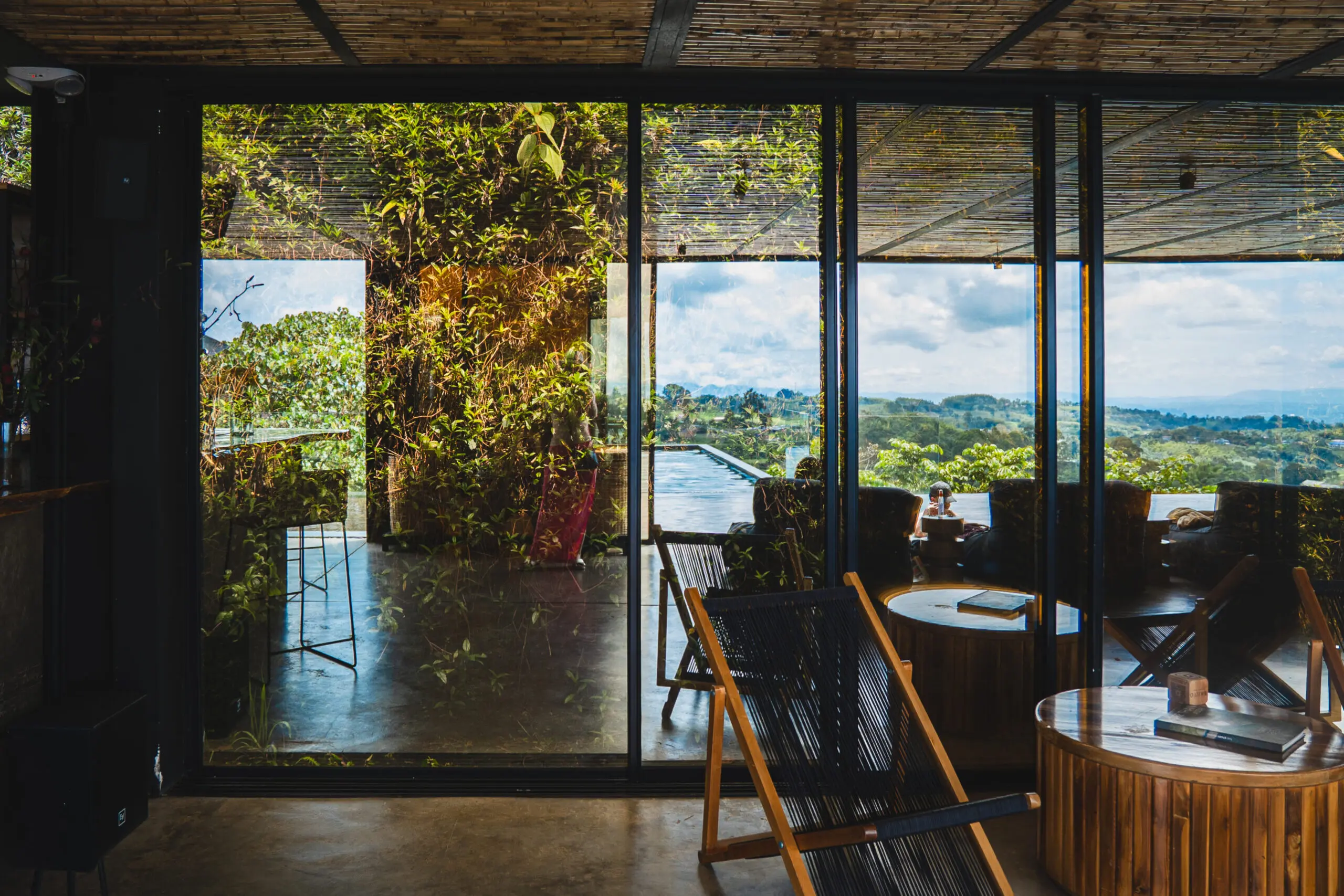 Cozy wooden chairs face a glass wall revealing scenic mountain views.