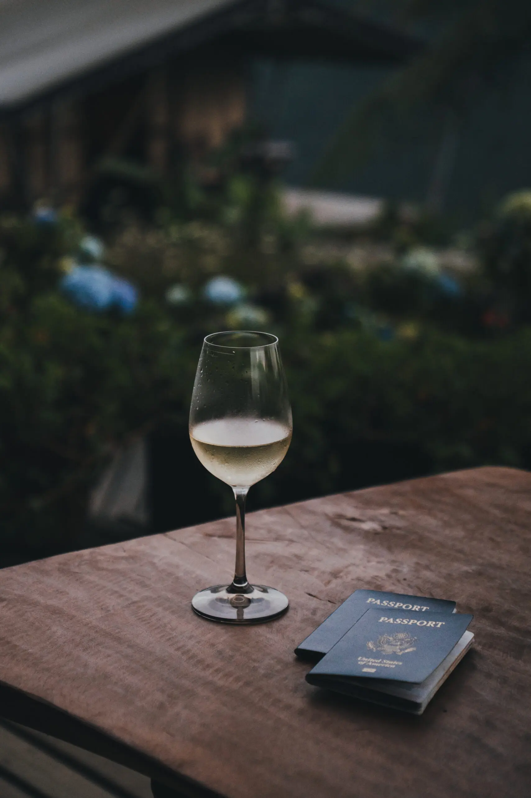 A glass of white wine on a wooden table outdoors with menus.