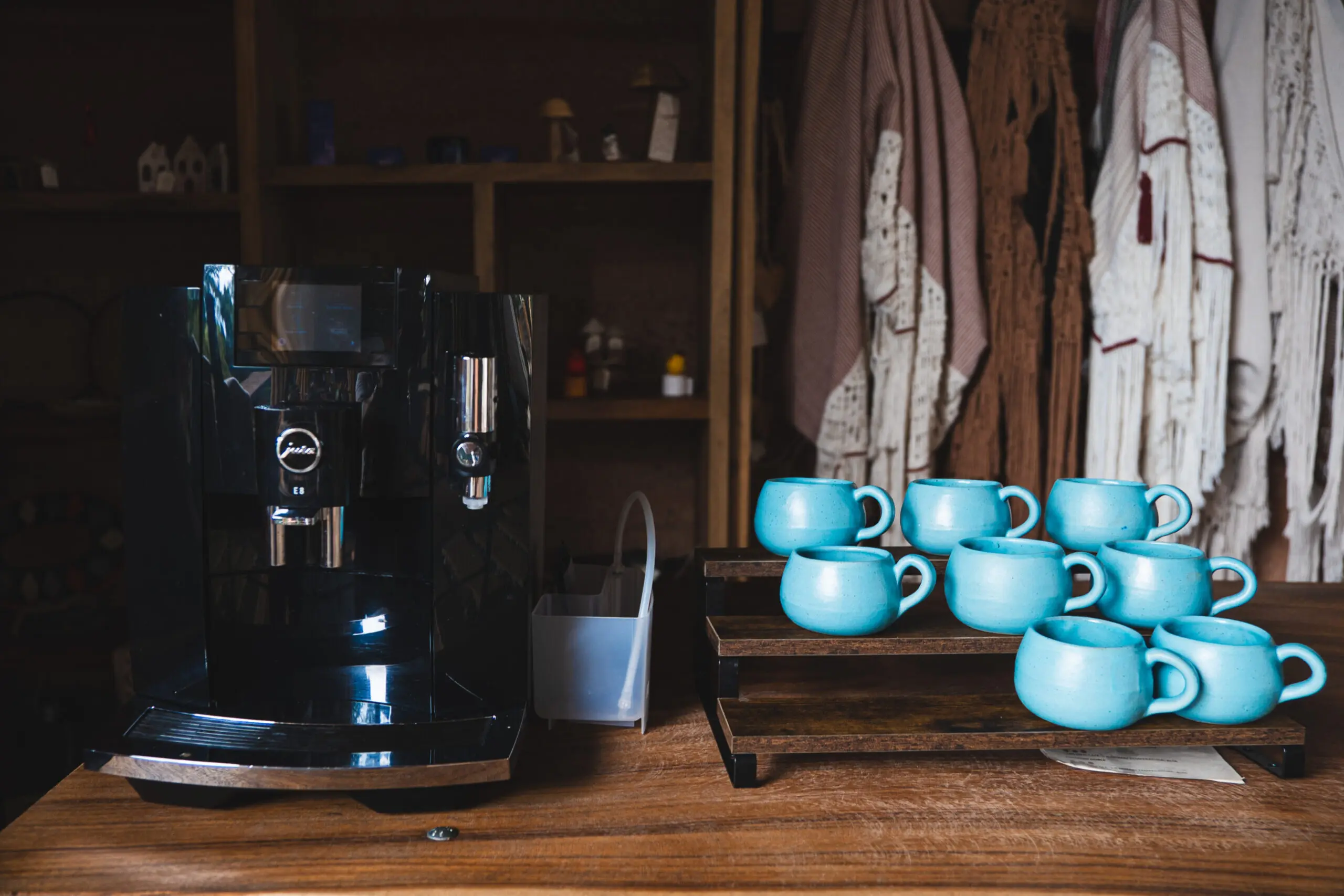 Black coffee machine next to blue cups on a wooden counter.