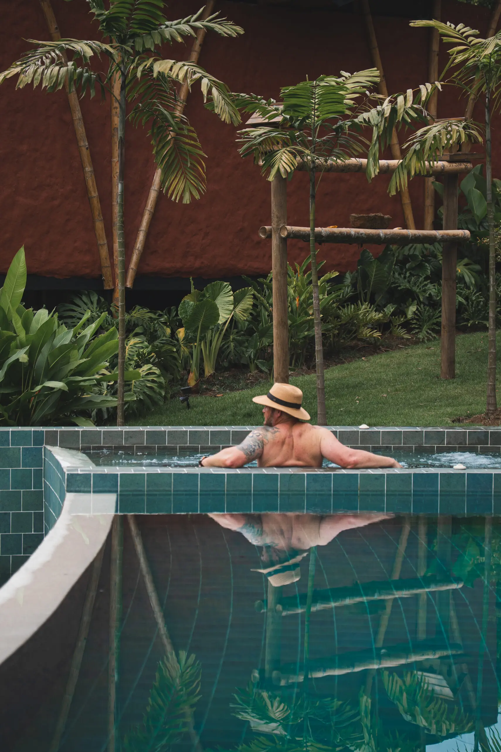 Person relaxing in a pool surrounded by greenery.